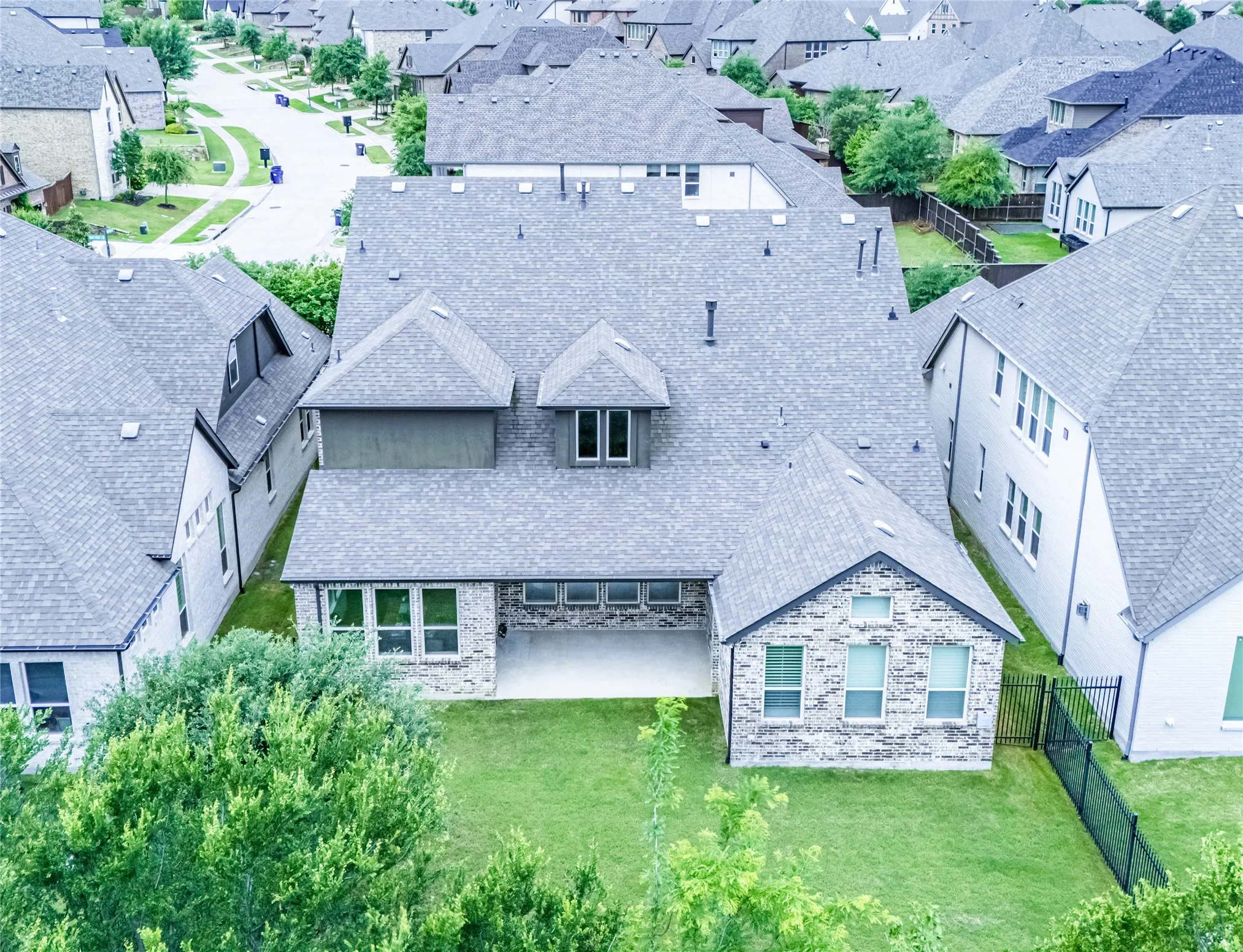 Rear exterior featuring a stone and siding facade, a covered patio, and a manicured lawn