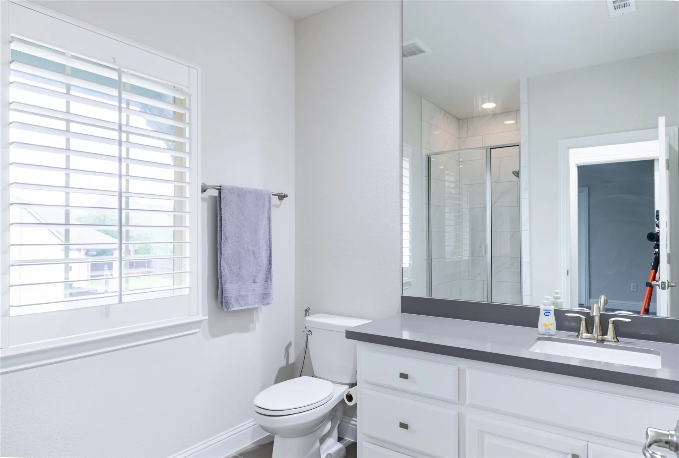 Contemporary bathroom featuring a white vanity with brushed nickel hardware, a gray countertop, an integrated rectangular sink, and a large mirror