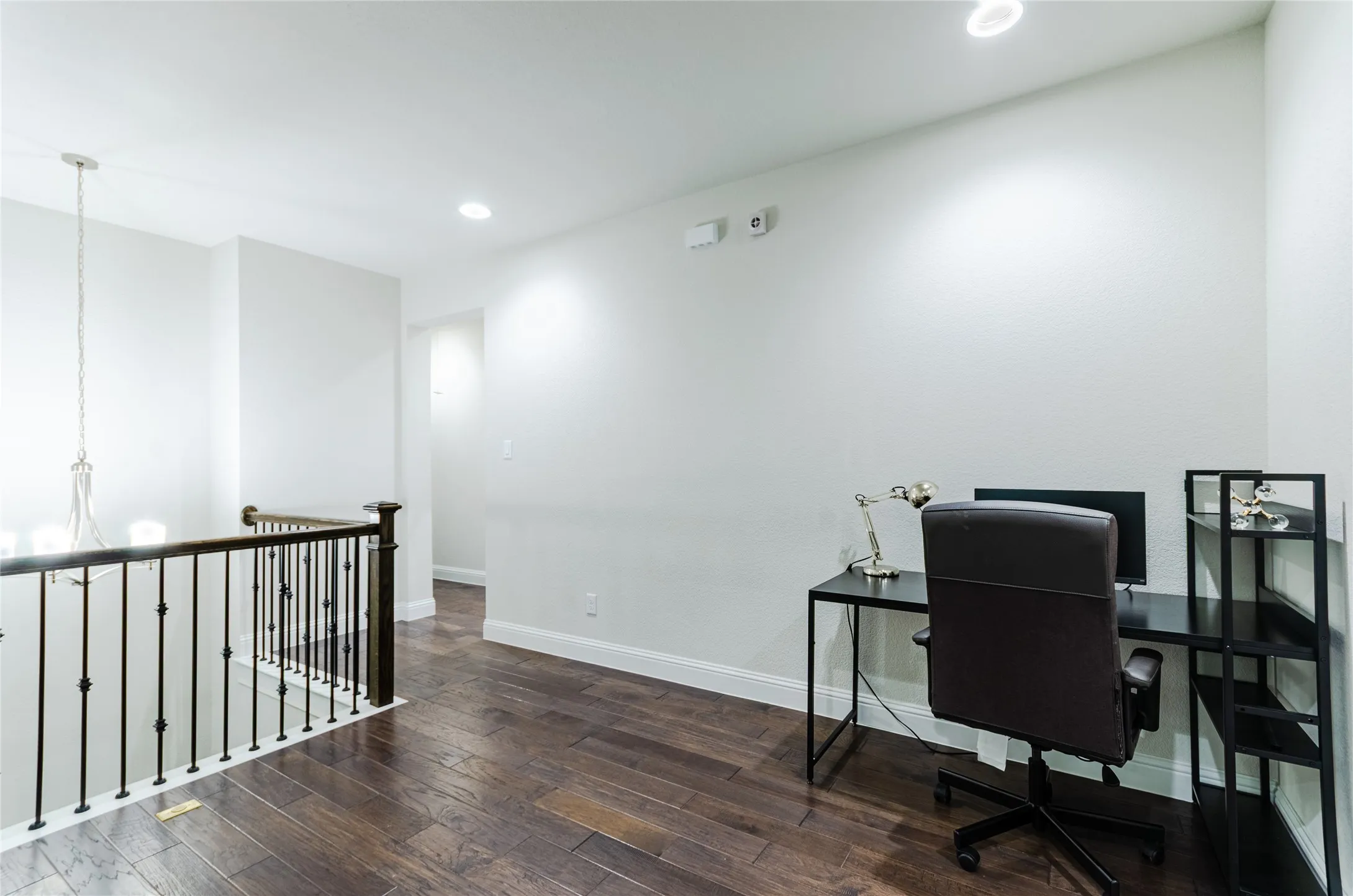 Open landing area featuring dark wood-finish flooring, white walls, and recessed lighting