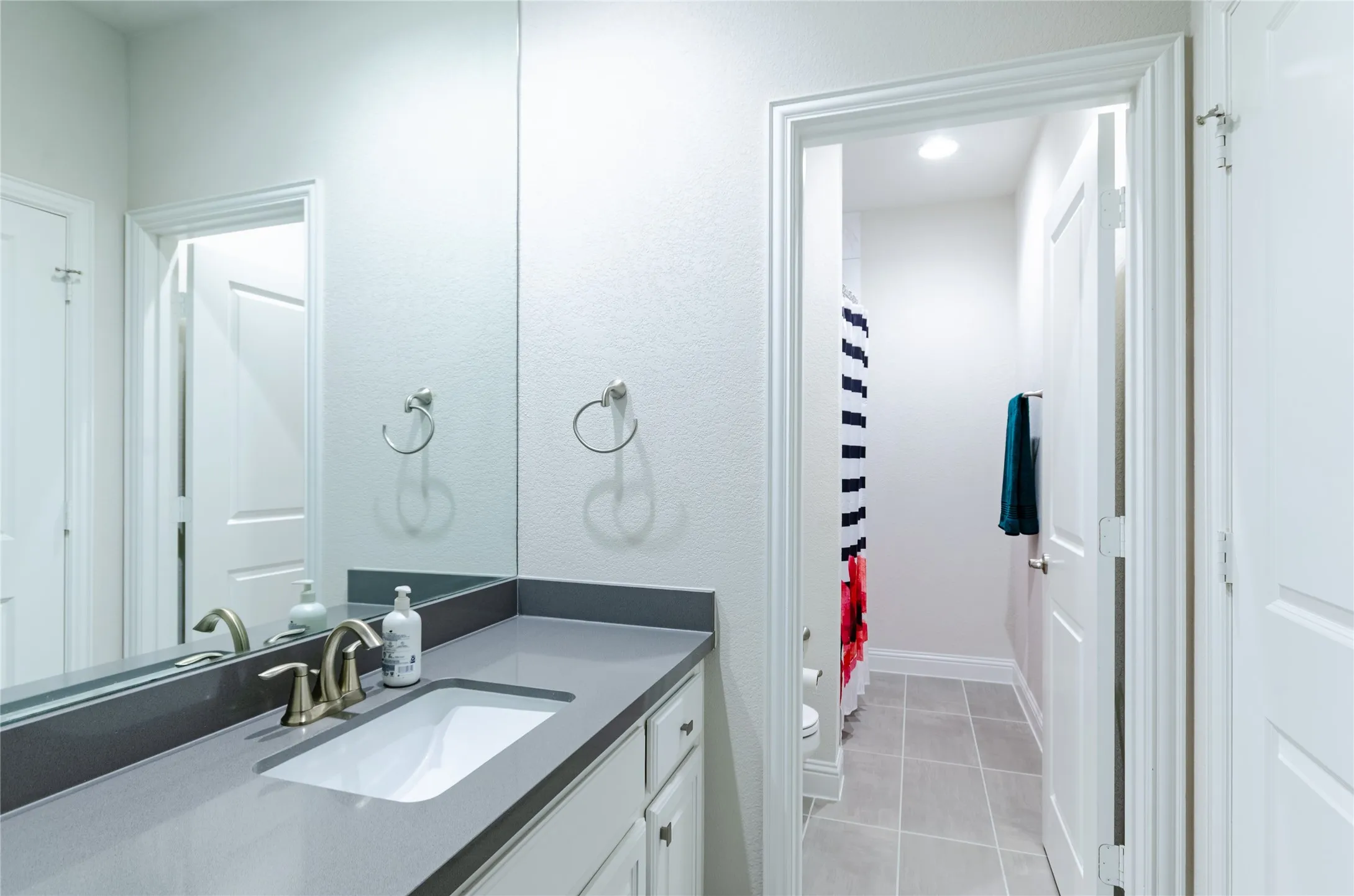 Bathroom vanity featuring a light gray countertop, undermount sink, and brushed nickel faucet