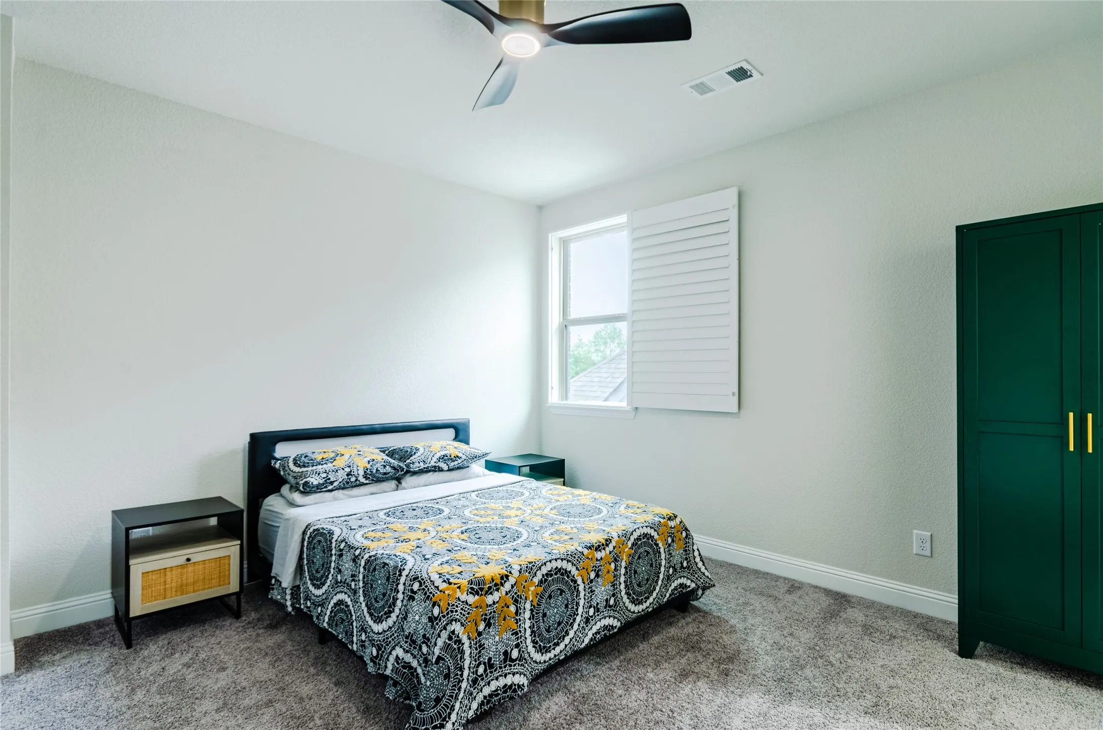 Bedroom featuring a window with white louvered shutters, light grey carpeting, and white baseboards