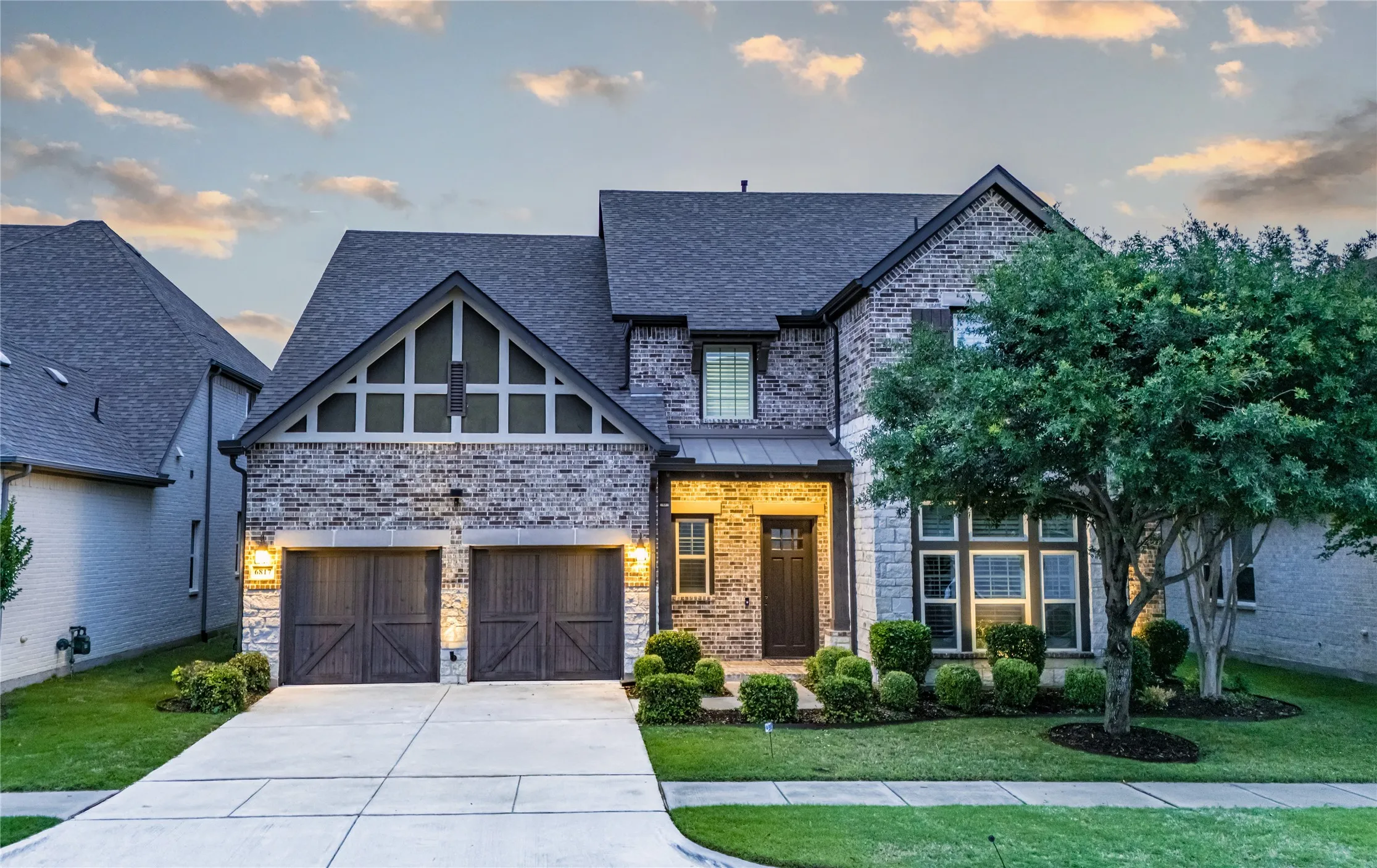 Stone and brick facade home featuring a two-car garage with wood-finish doors