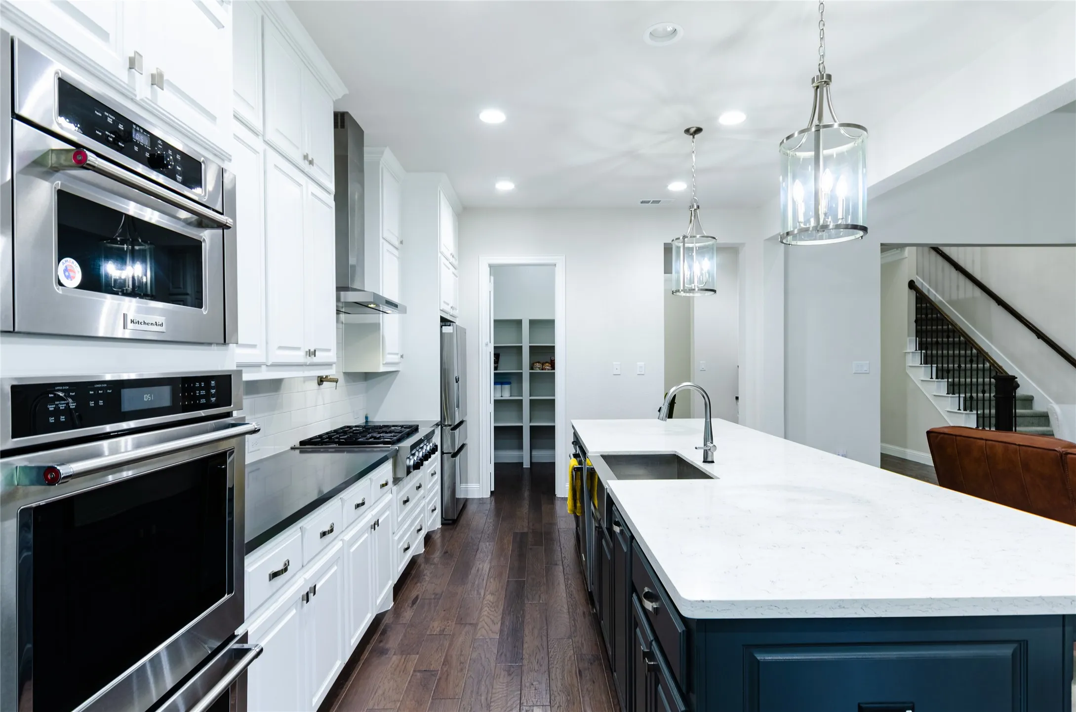 Kitchen featuring a spacious island with an undermount sink, pendant lighting, and white perimeter cabinetry