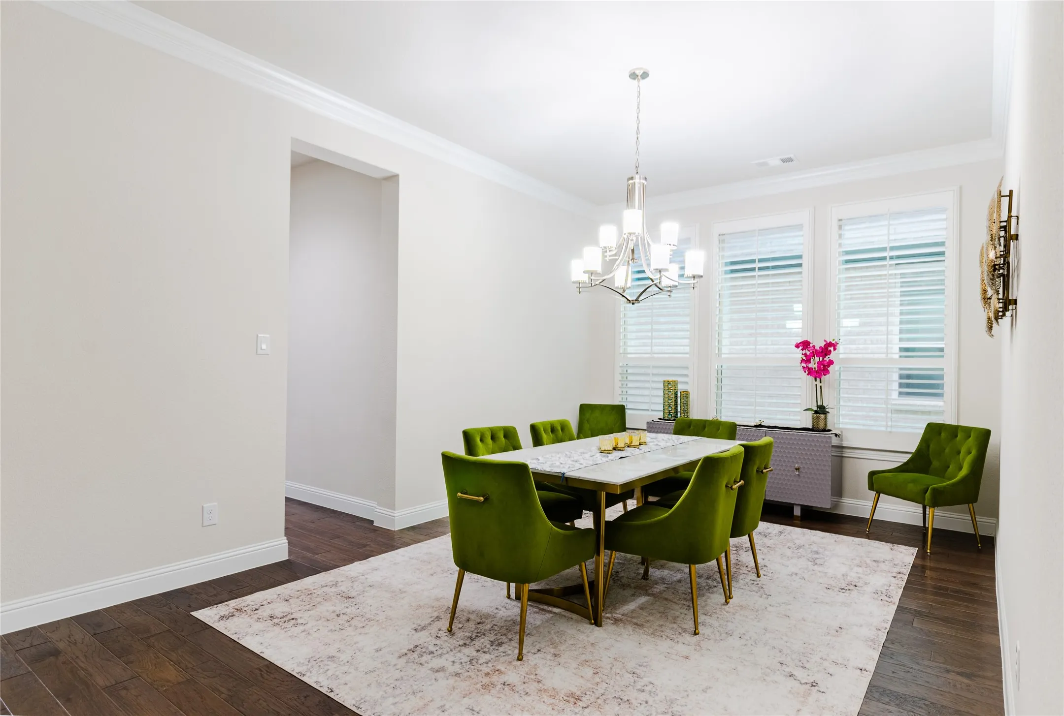 Formal dining area featuring rich wood-finish flooring and extensive crown molding