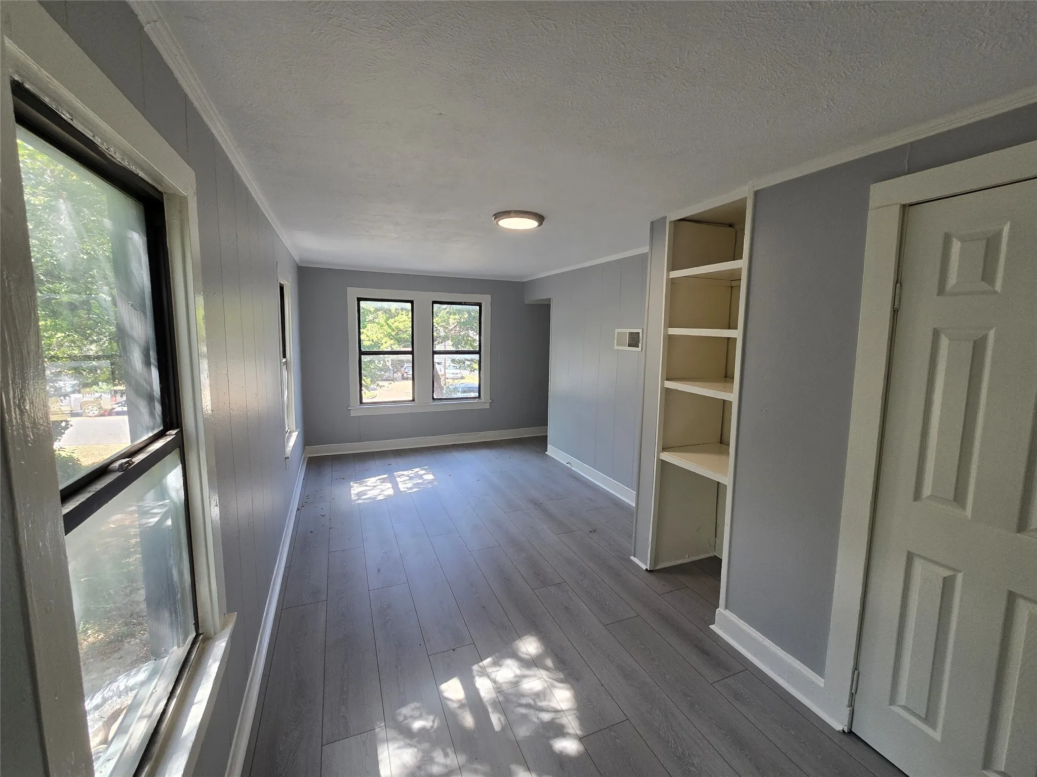 Wood-finish flooring, built-in shelving, white trim, and multiple​​‌​​​​‌​​‌‌​‌‌​​​‌‌​‌​‌​‌​​​‌​​ windows