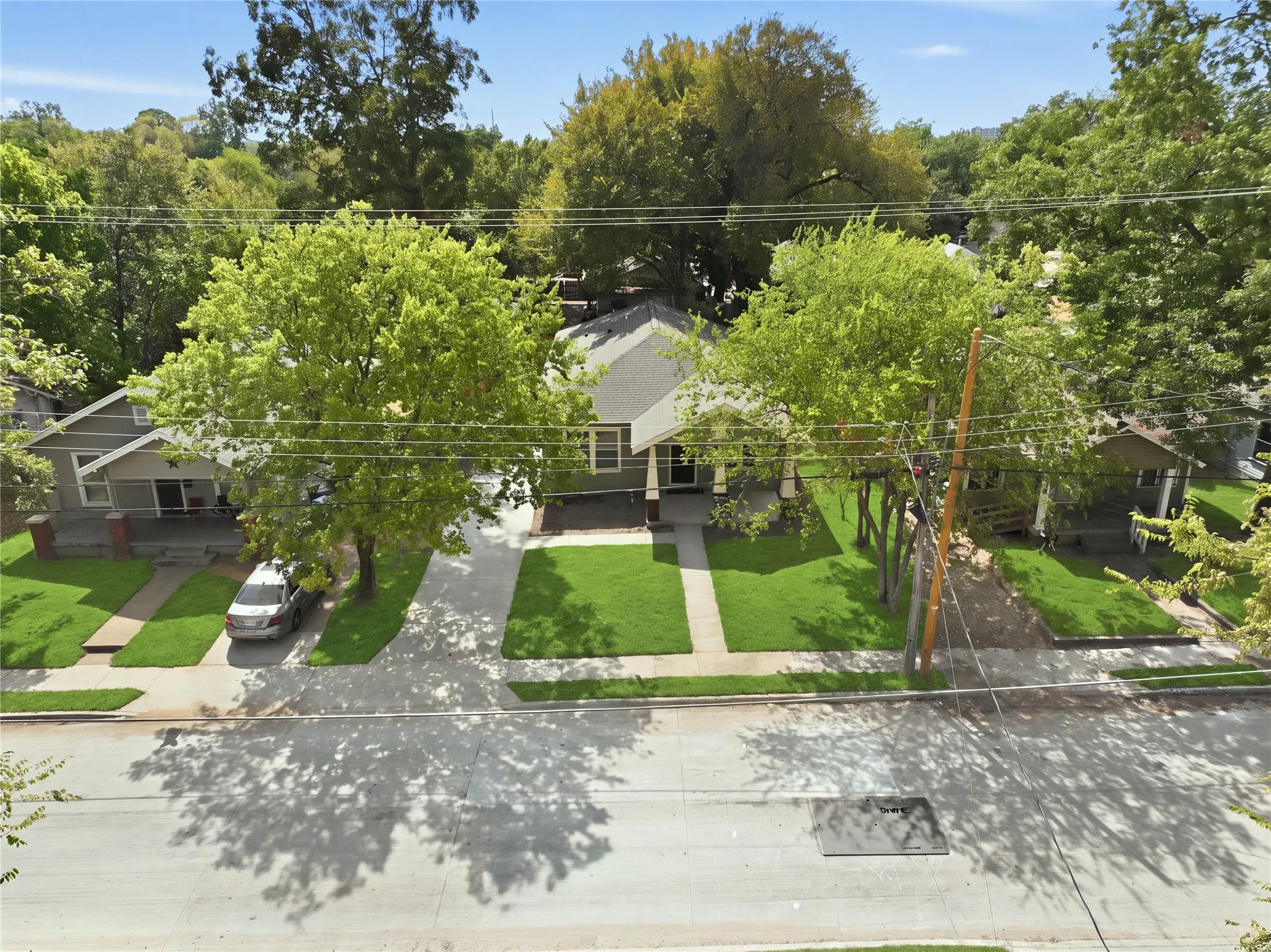 Gabled roofline, concrete driveway, front porch, mature trees, manicured lawn