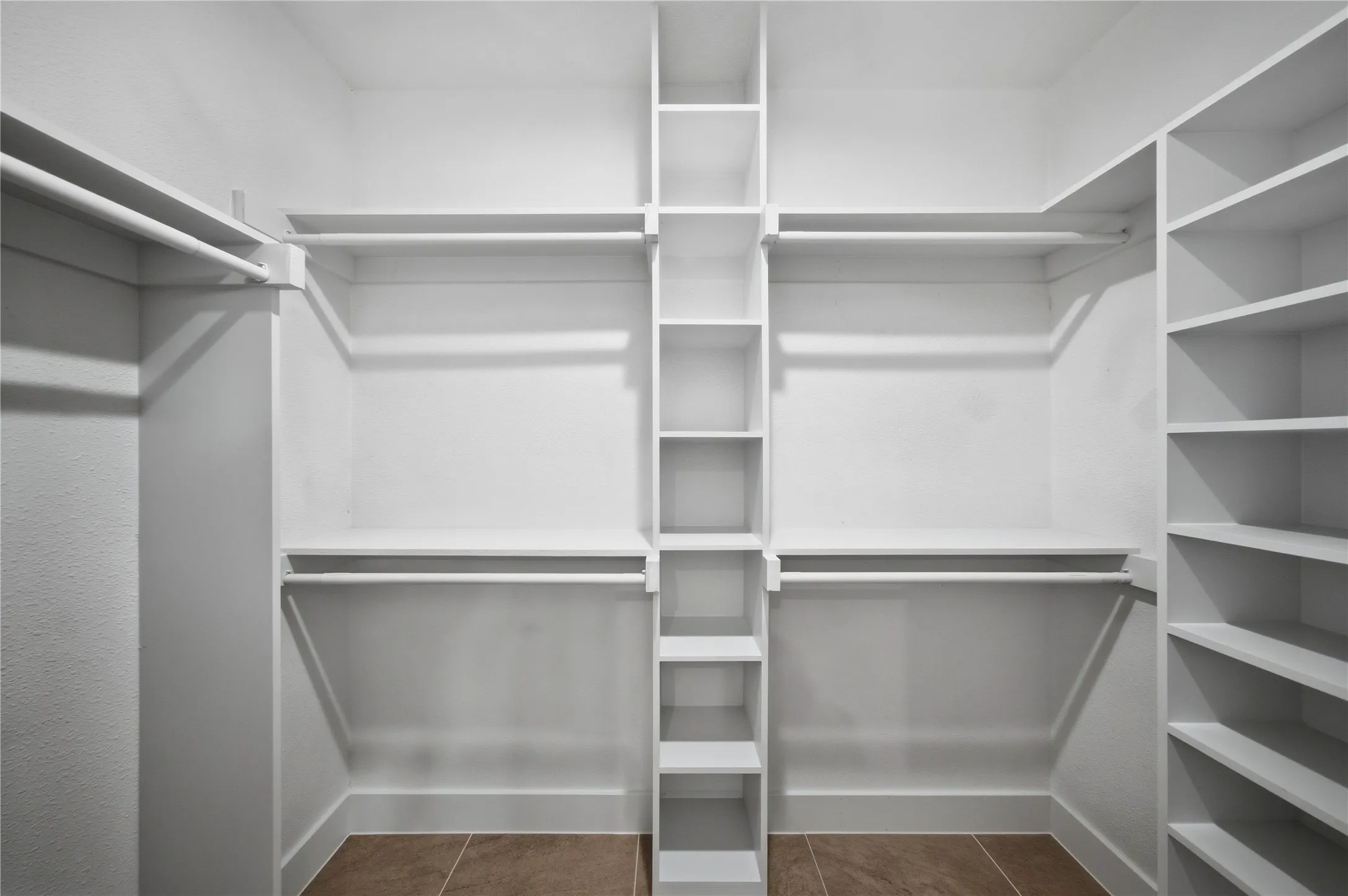 Walk-in closet with extensive built-in shelving, multiple hanging rods, and an integrated central shelving unit