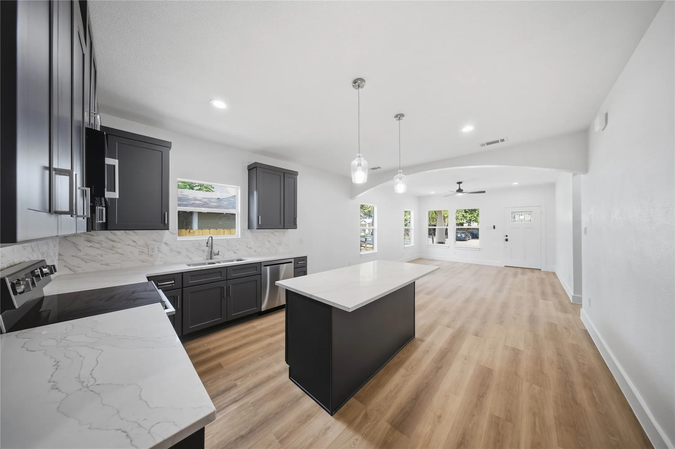 Kitchen featuring dark cabinetry, stainless steel appliances, light countertops, and wood-finish flooring