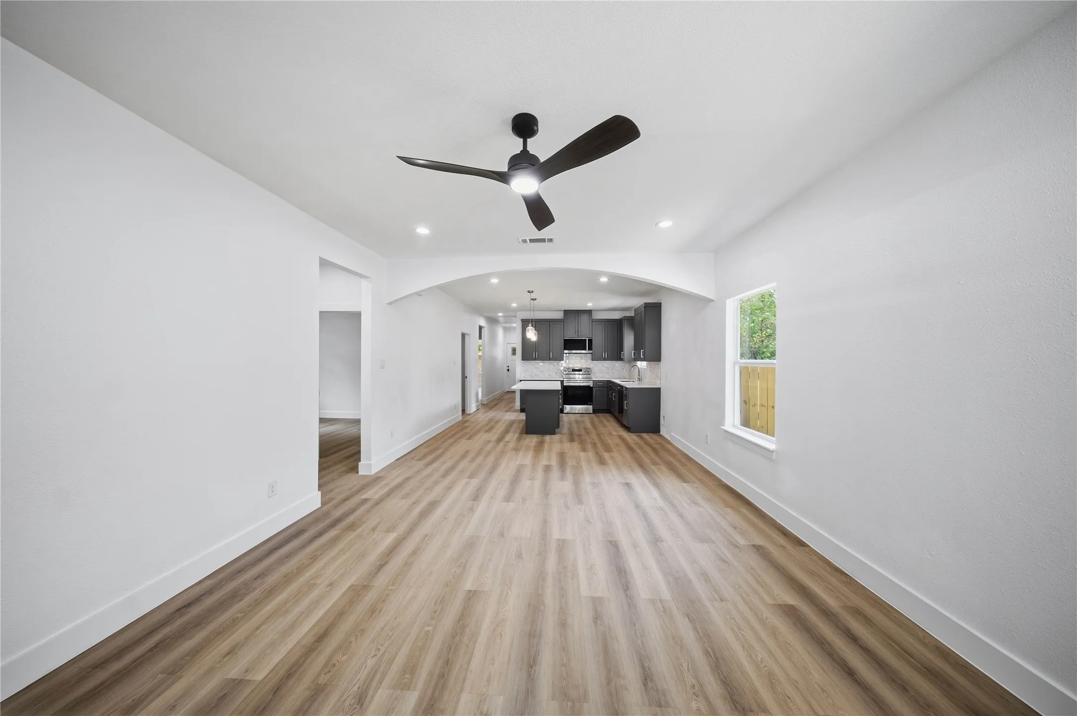 Spacious interior with wood-finish flooring, recessed lighting, and a contemporary ceiling fan