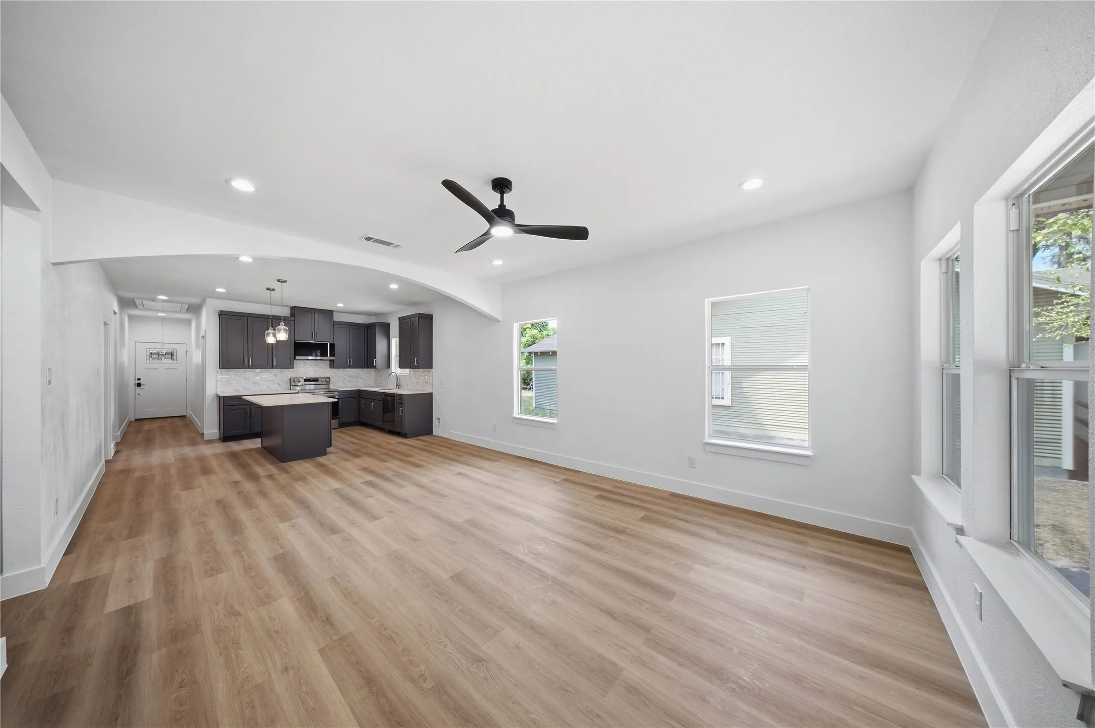 Open-concept living space with wood-finish flooring, vaulted ceilings, and recessed lighting