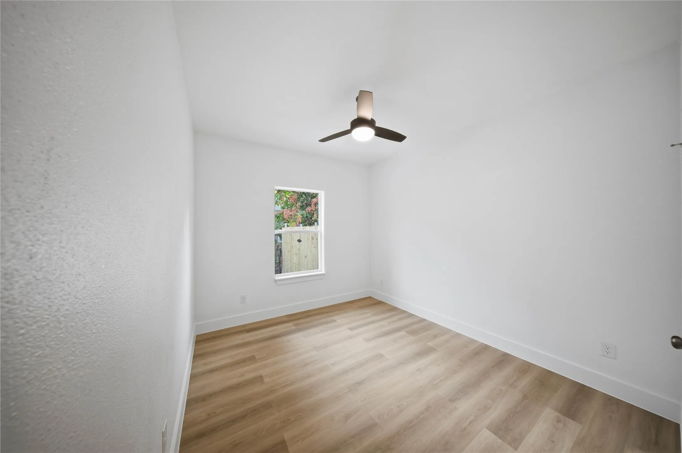 Recessed window with wood-finish flooring, white walls, and a ceiling fan with integrated lighting