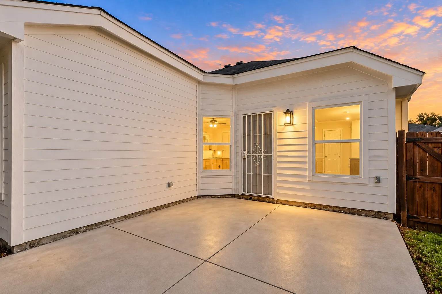 Exterior featuring white horizontal siding, a concrete patio, and a wood privacy fence