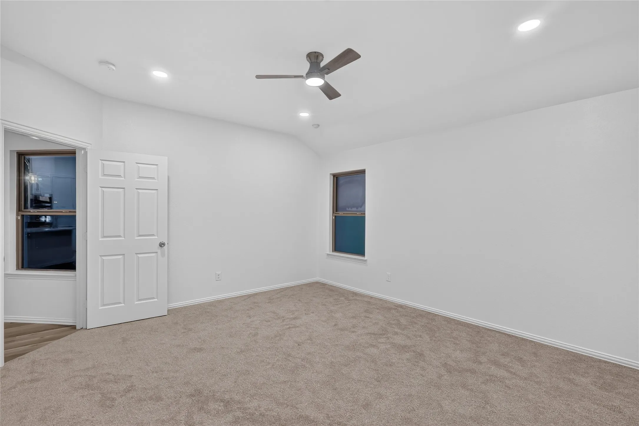 Neutral tone carpeting with white walls, recessed lighting, and a ceiling fan