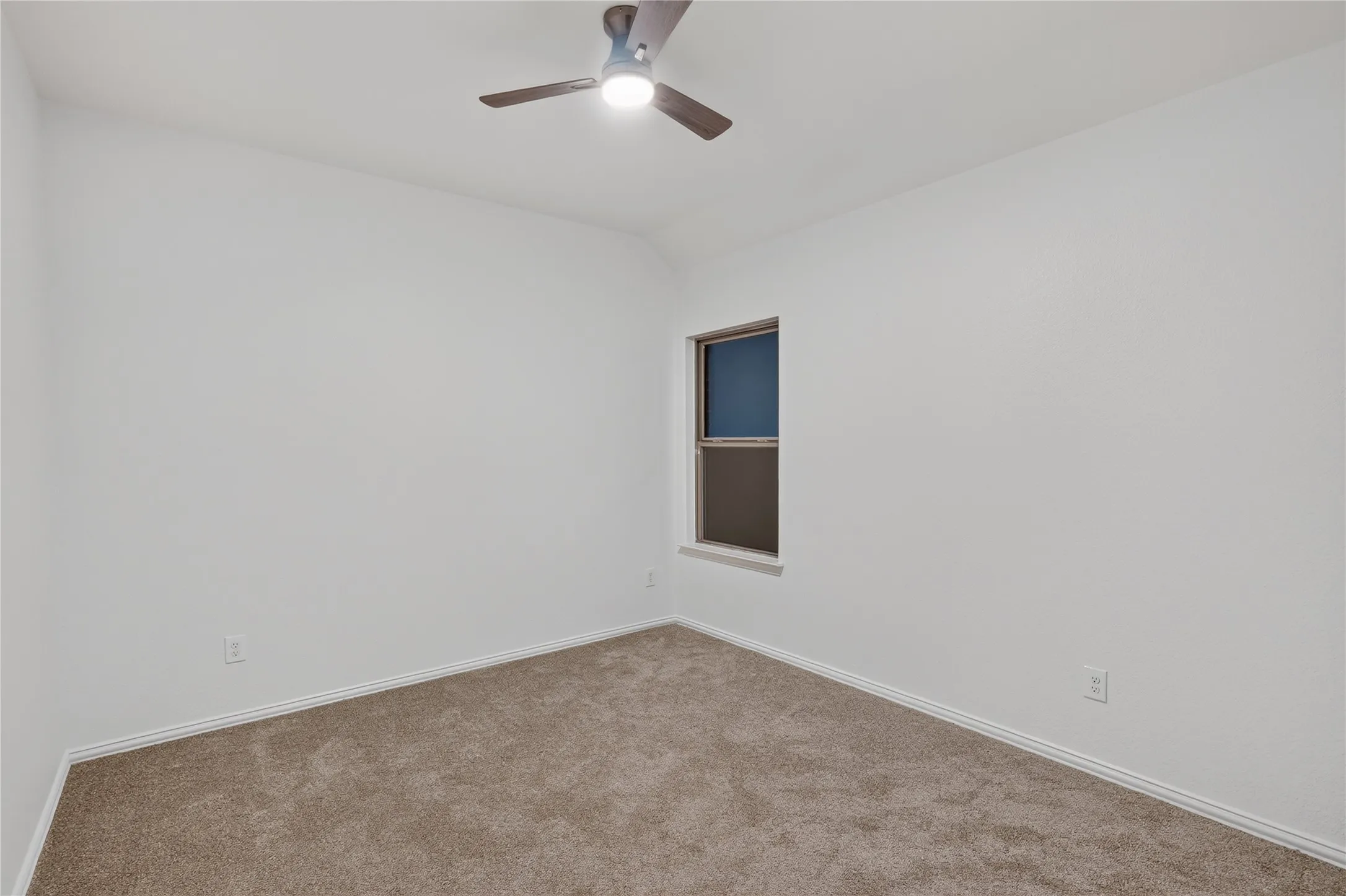Neutral tone wall finish with a single window, ceiling fan, and carpeted flooring