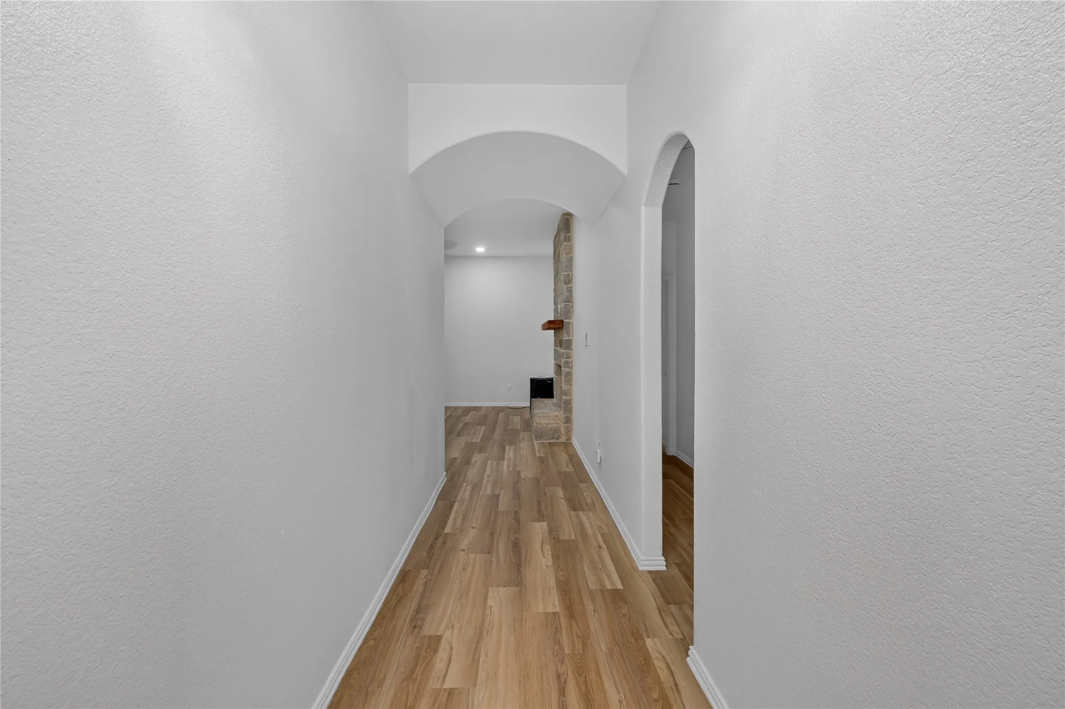 Wood-finish flooring throughout, arched entryway, and recessed lighting