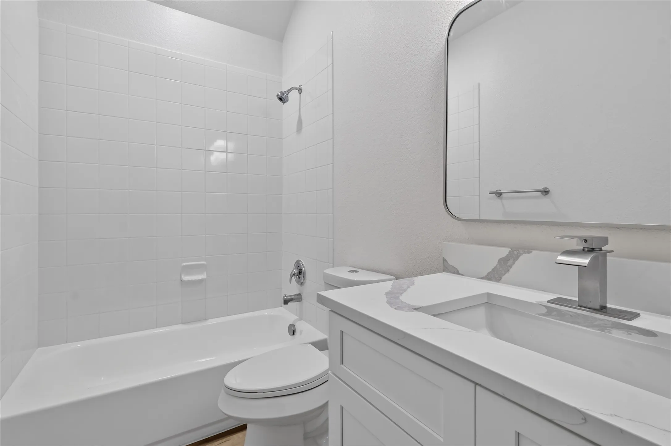 White subway tile shower surround with a built-in tub, sleek vanity with an integrated sink, and an elegant wall-mounted mirror