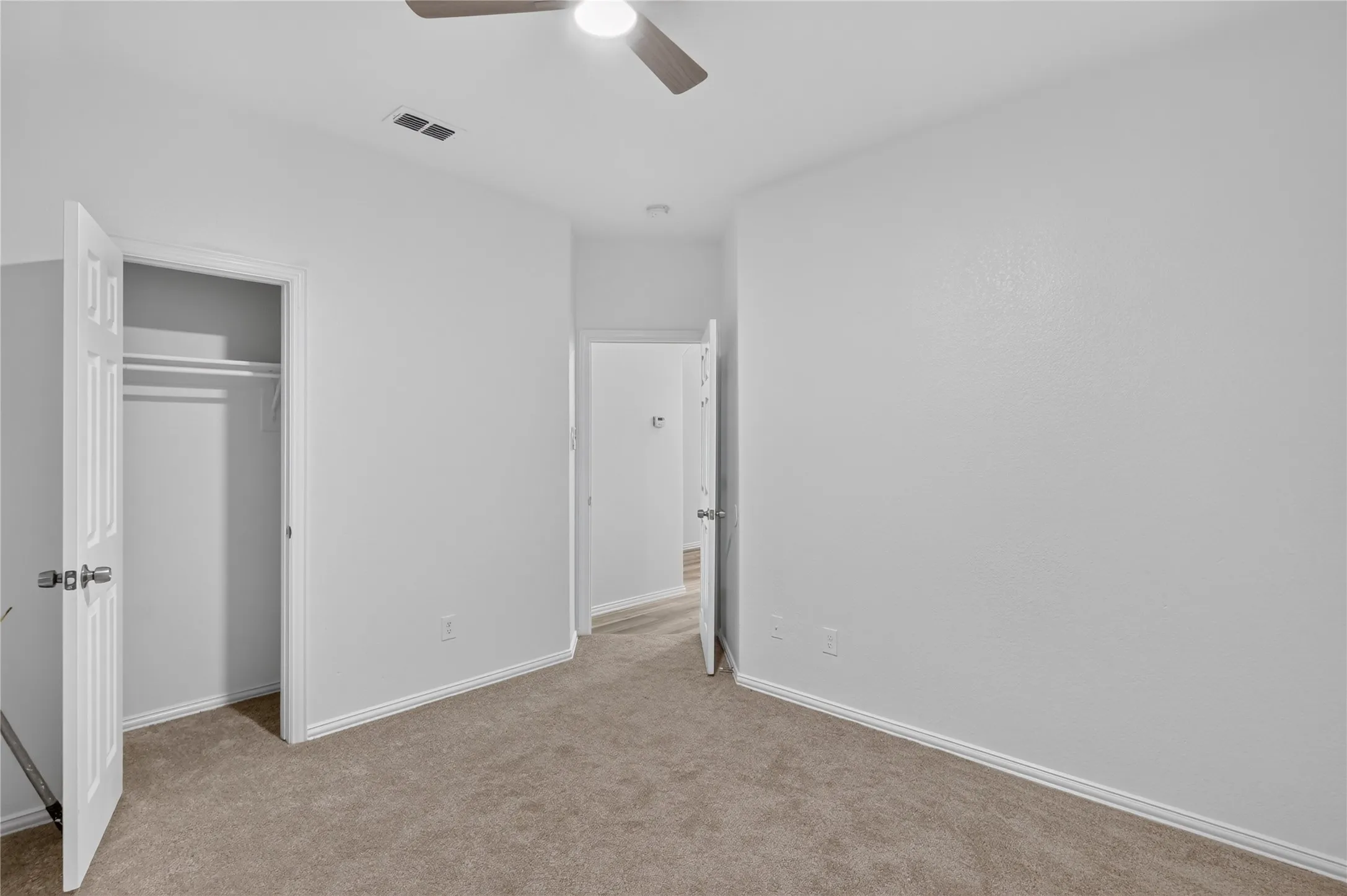 Carpeted flooring, ceiling fan with integrated lighting, white interior doors, and built-in closet with shelving