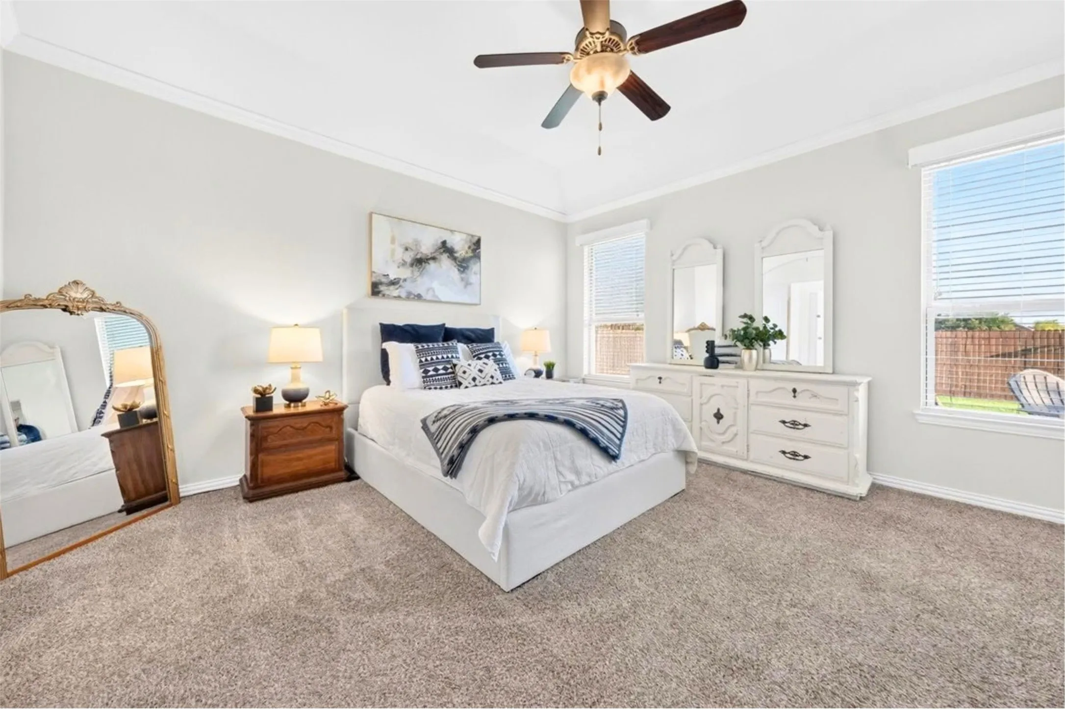 Tray ceiling with crown molding, ceiling fan, carpeting, and multiple windows
