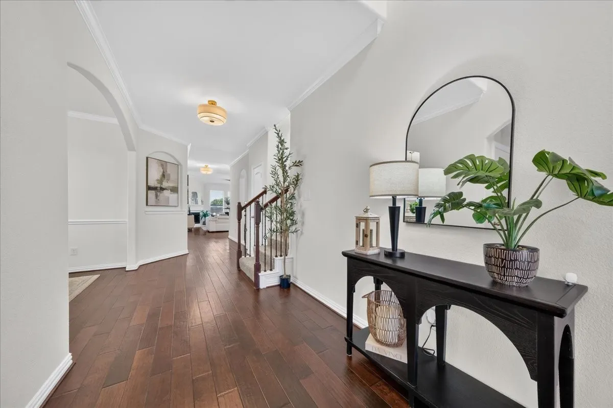 Elegant foyer showcasing rich wood-finish flooring, white shaker-style wall paneling, and a coffered ceiling with recessed lighting