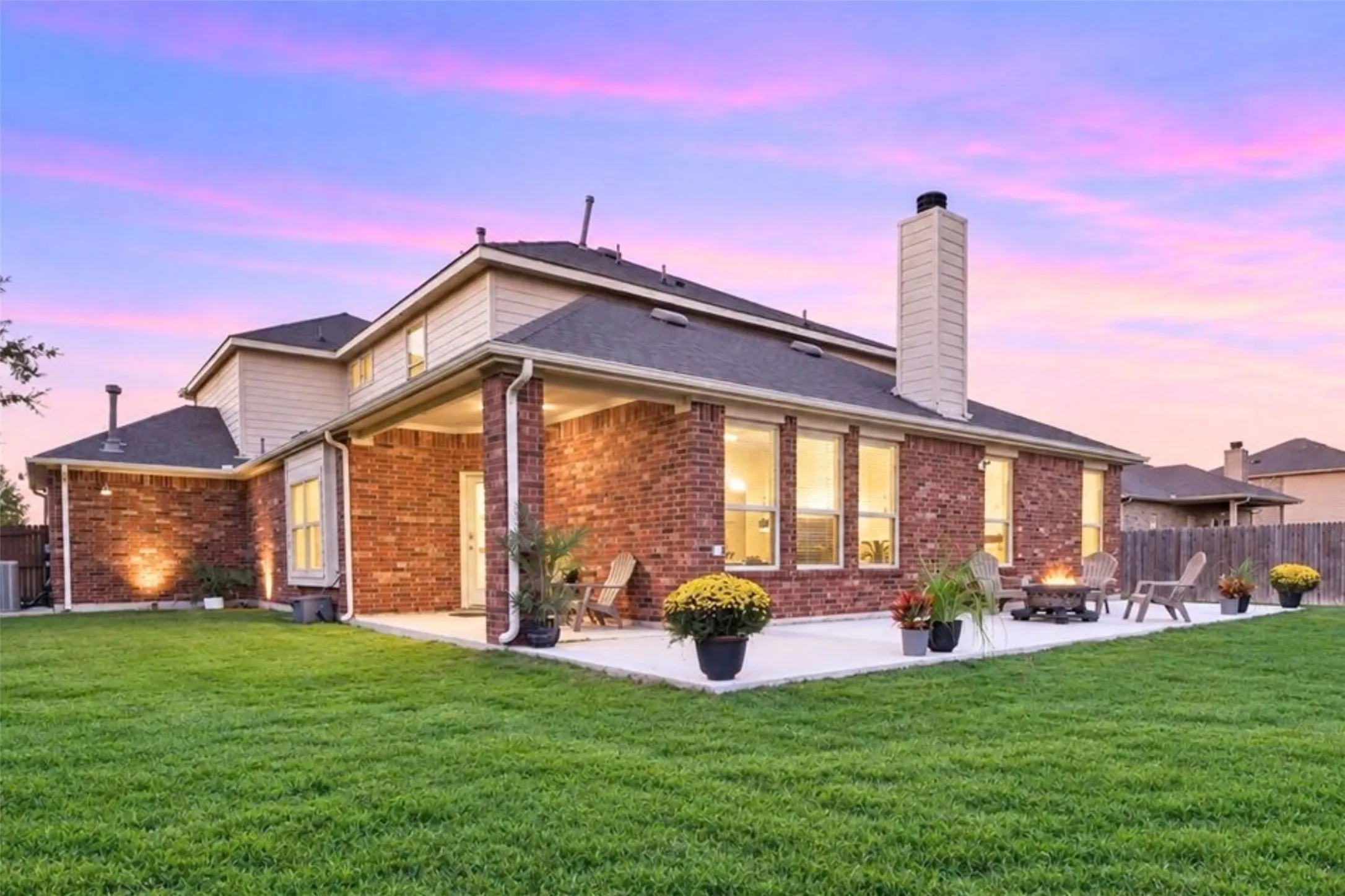 Expansive backyard featuring a large concrete patio, covered porch area, and a brick exterior
