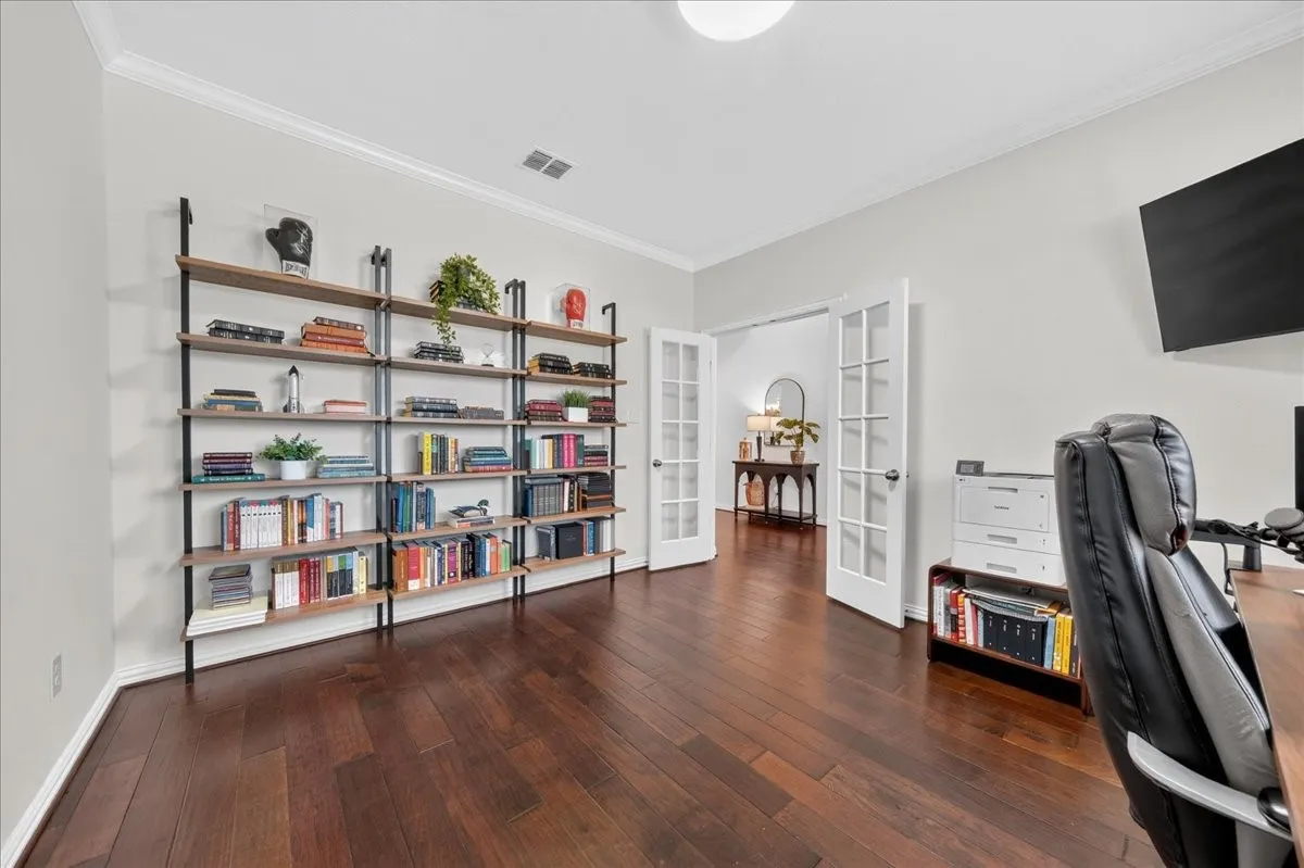 Hardwood flooring, crown molding, built-in shelving, and French doors