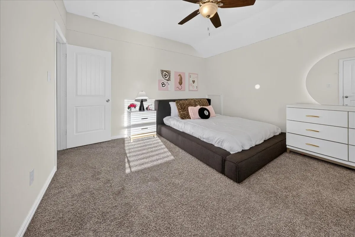Ceiling fan with light fixture, white interior door, light-colored walls, and carpeting