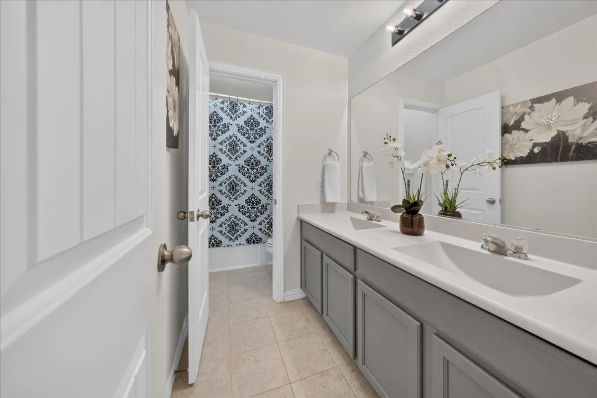 Double vanity with integrated sinks, gray shaker-style cabinetry, and a large wall-mounted mirror