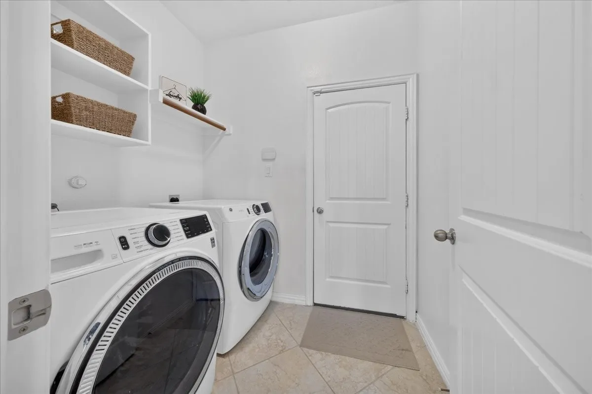 Laundry area featuring built-in shelving, a wood-finish hanging rod, and tiled flooring