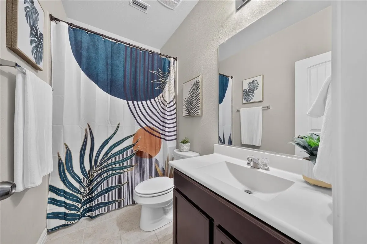 Bathroom featuring a single vanity with a white countertop and dark wood-finish cabinetry, a mirror, and a toilet