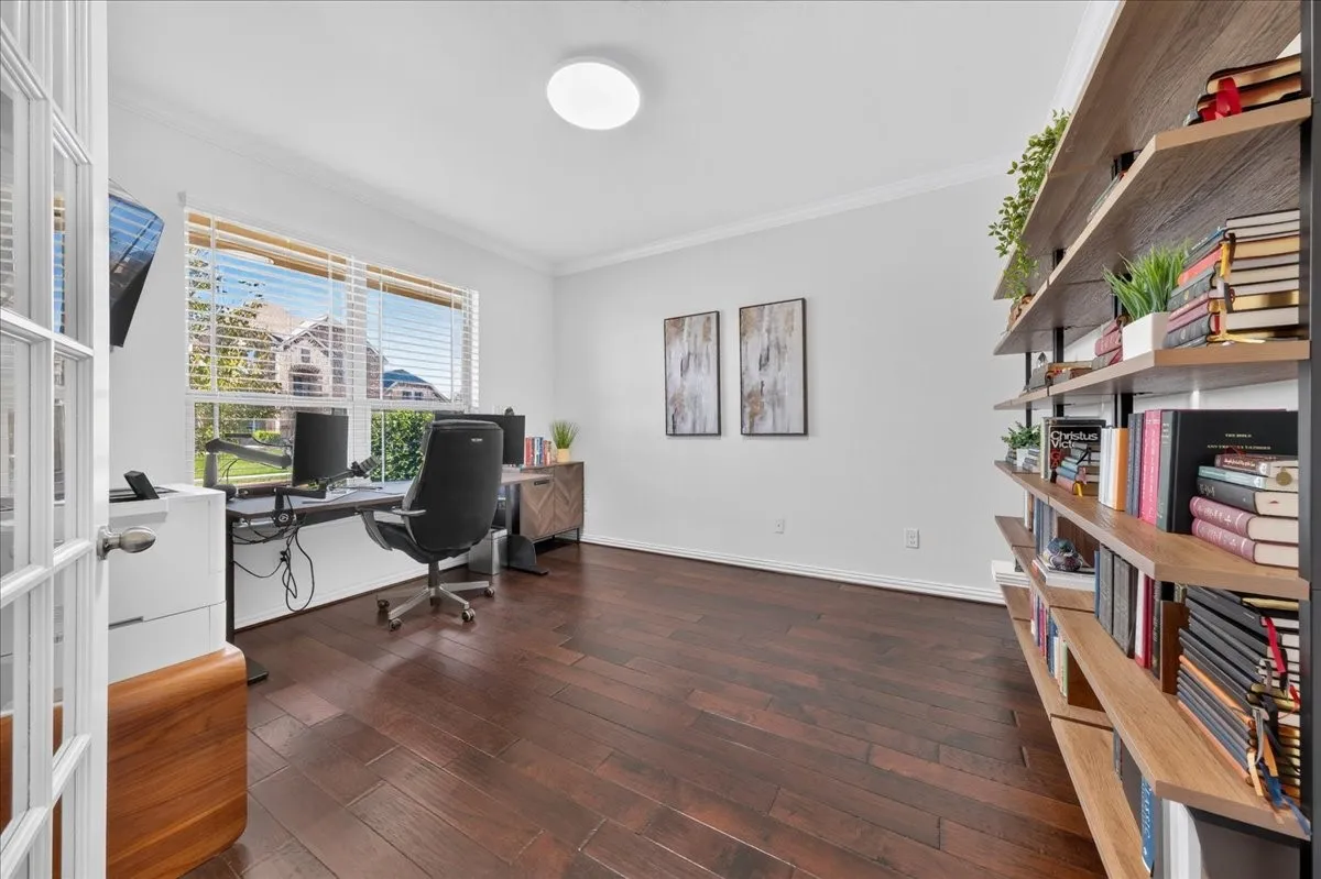 Wood-finish flooring, built-in shelving, white walls, and a large window with blinds