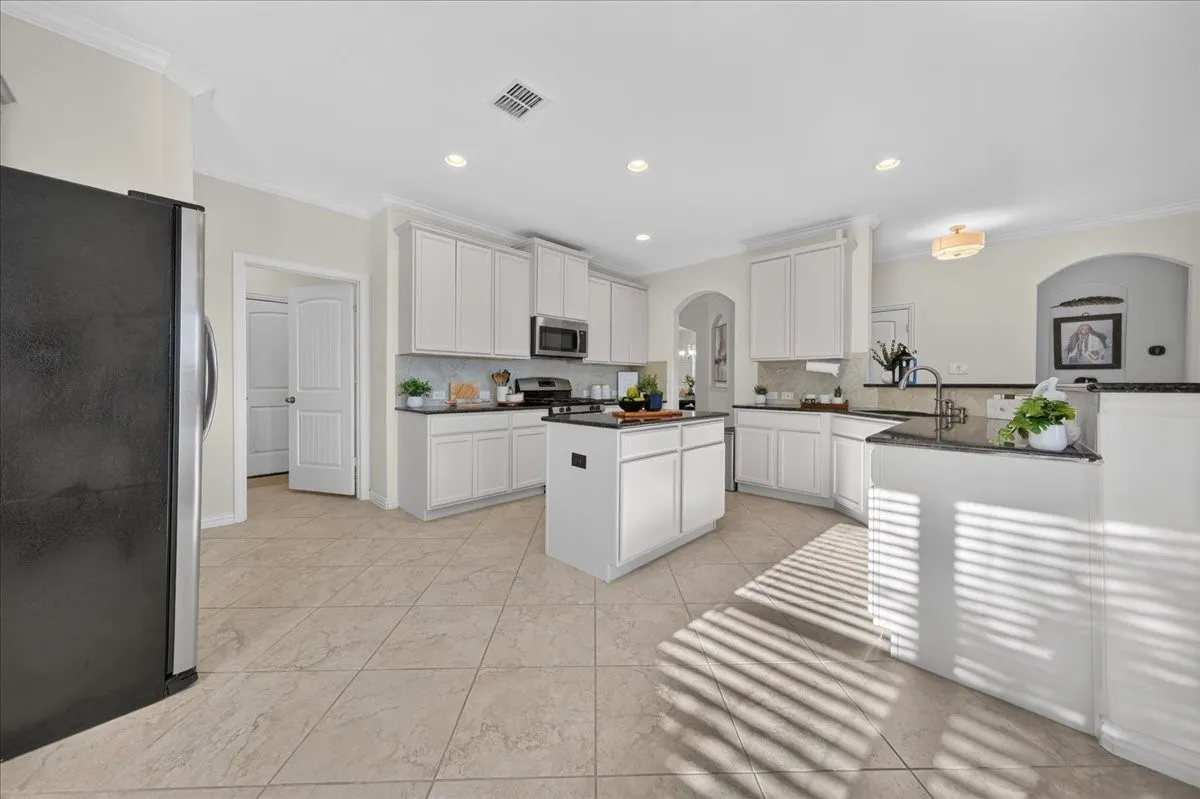 Kitchen featuring white cabinetry, dark countertops, a central island, recessed lighting, and tile flooring