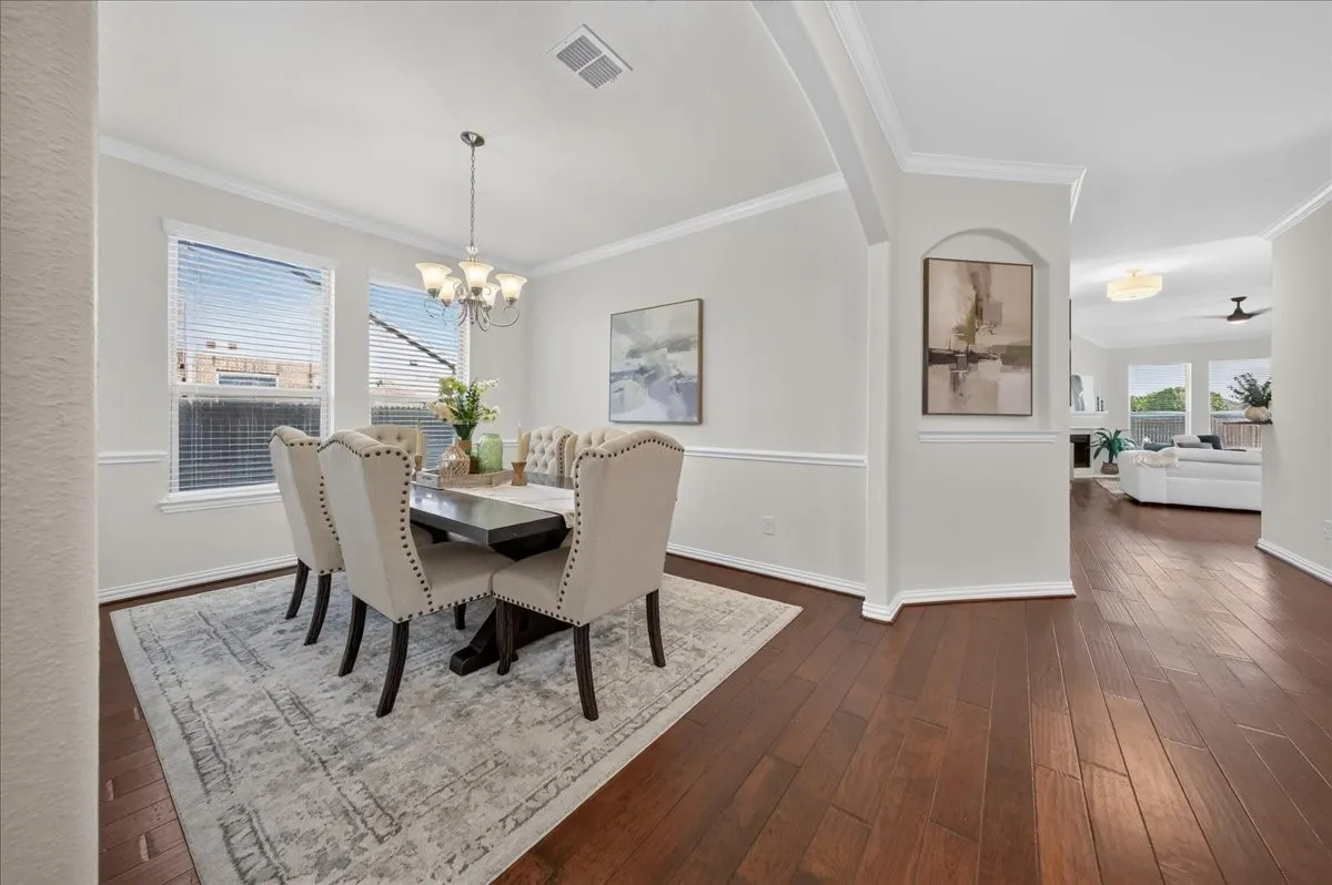 Wood-finish flooring, crown molding, chair rail, and multiple windows with blinds