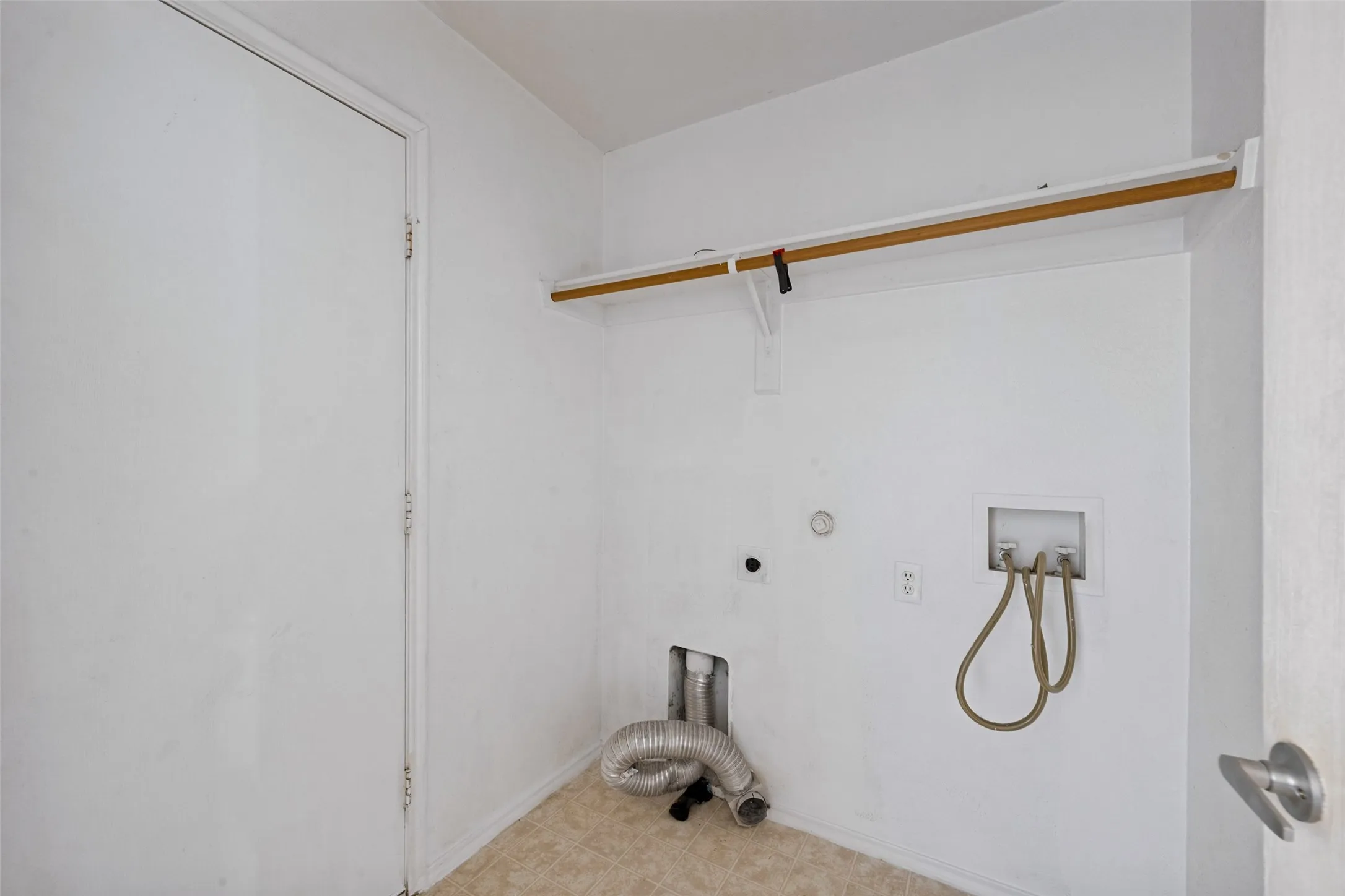 Utility area featuring a wall-mounted clothes rod and connections for laundry appliances