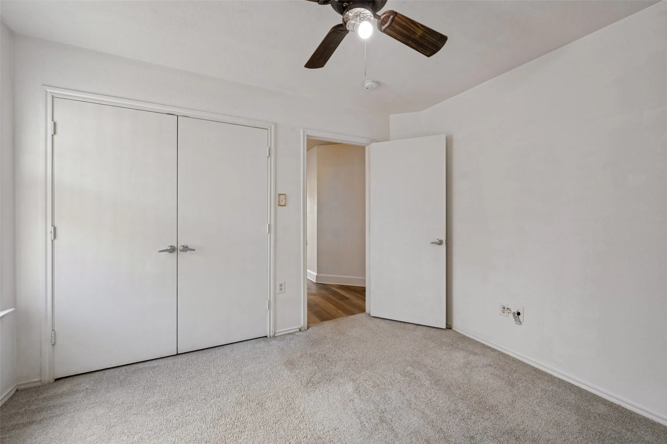 Light-colored carpeting with a ceiling fan and overhead lighting
