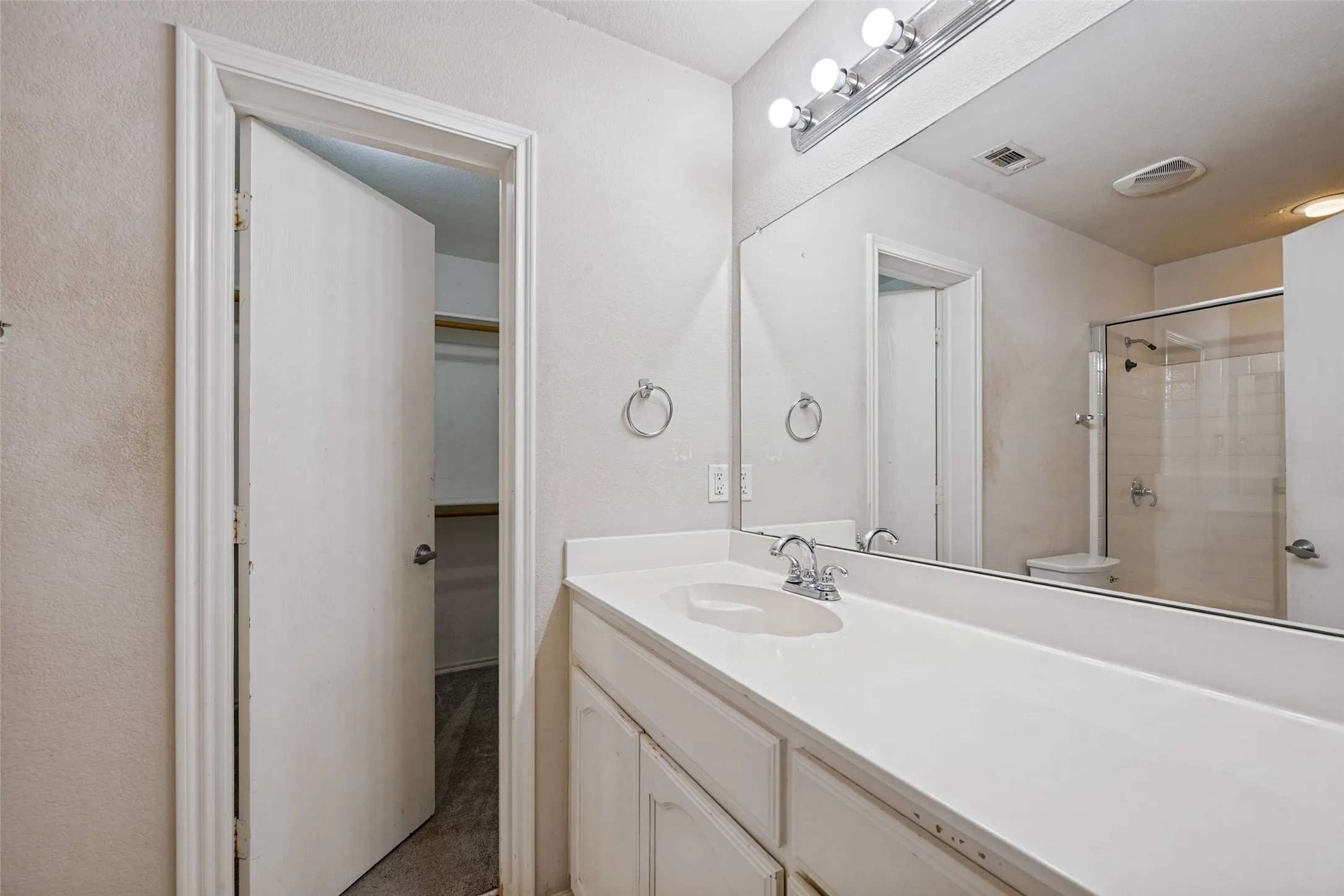 Vanity with a single basin, a chrome faucet, and a large mirror