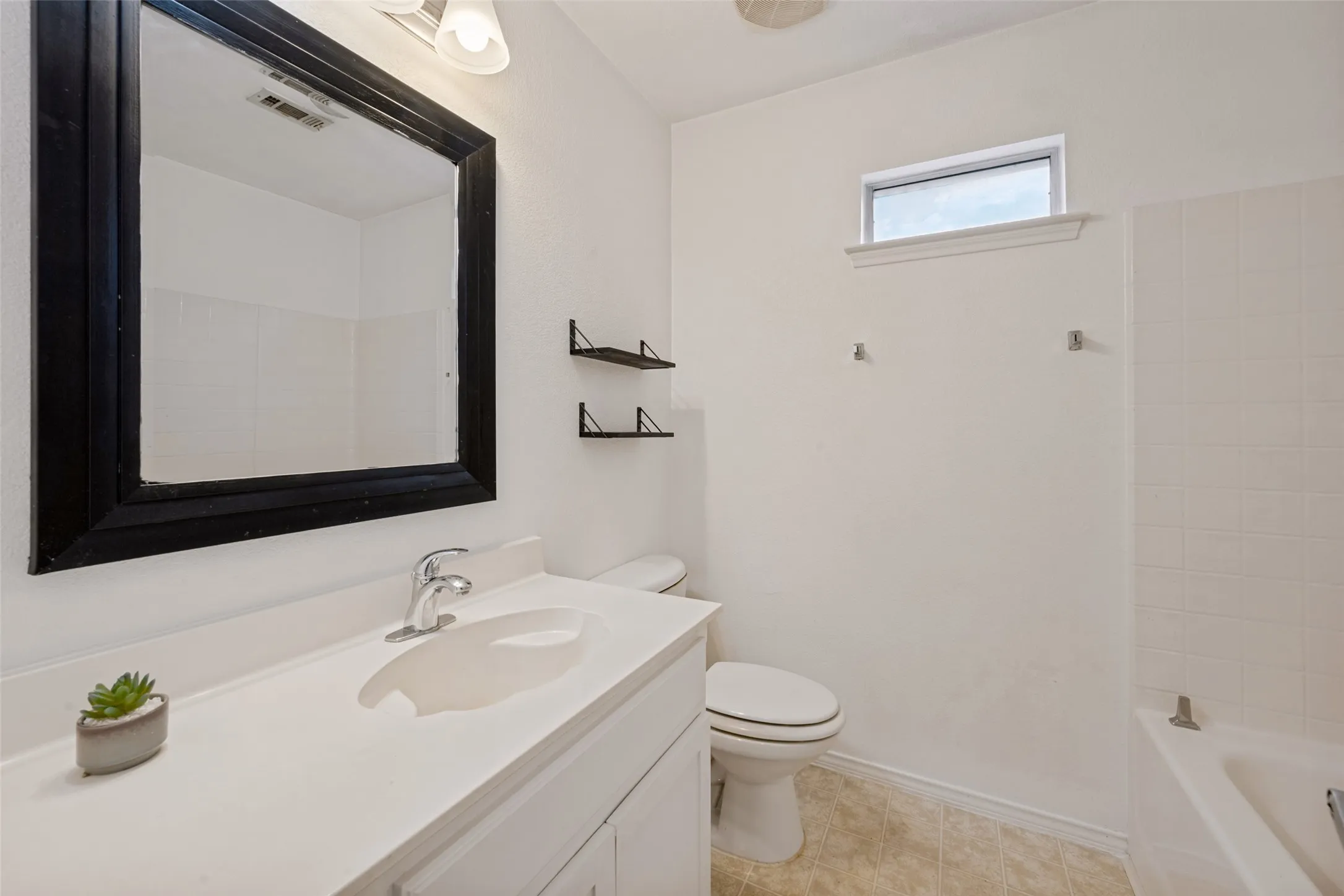 White vanity with an integrated sink, polished chrome faucet, and a large framed mirror