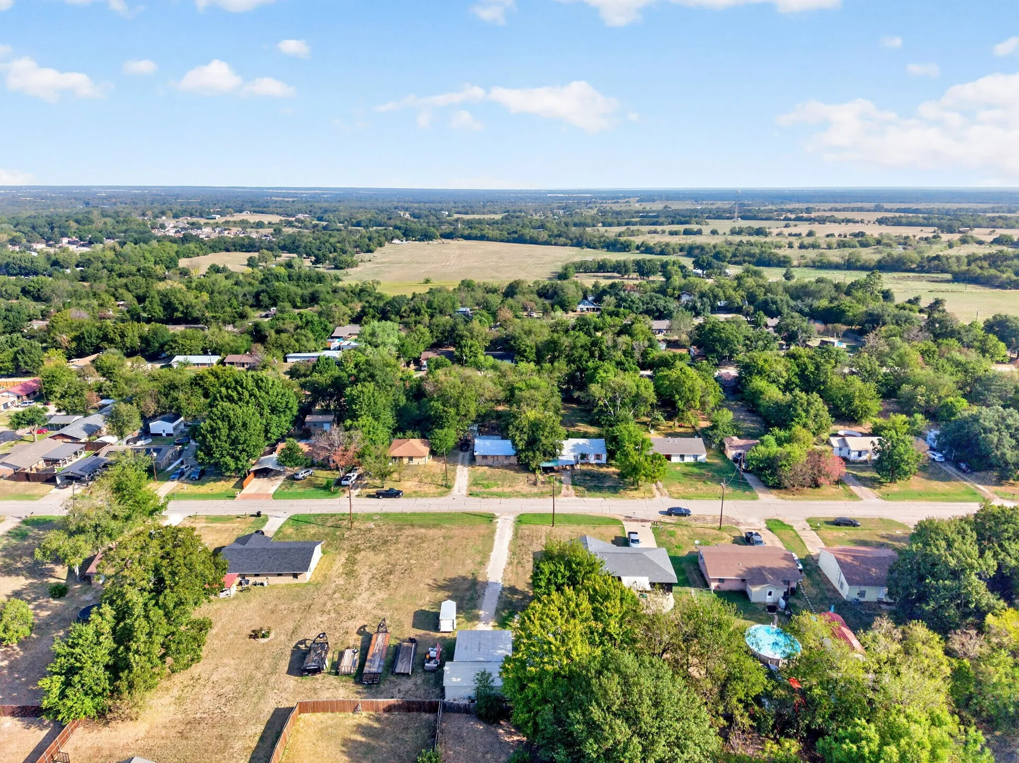 Residential area with mature trees and open fields in the background