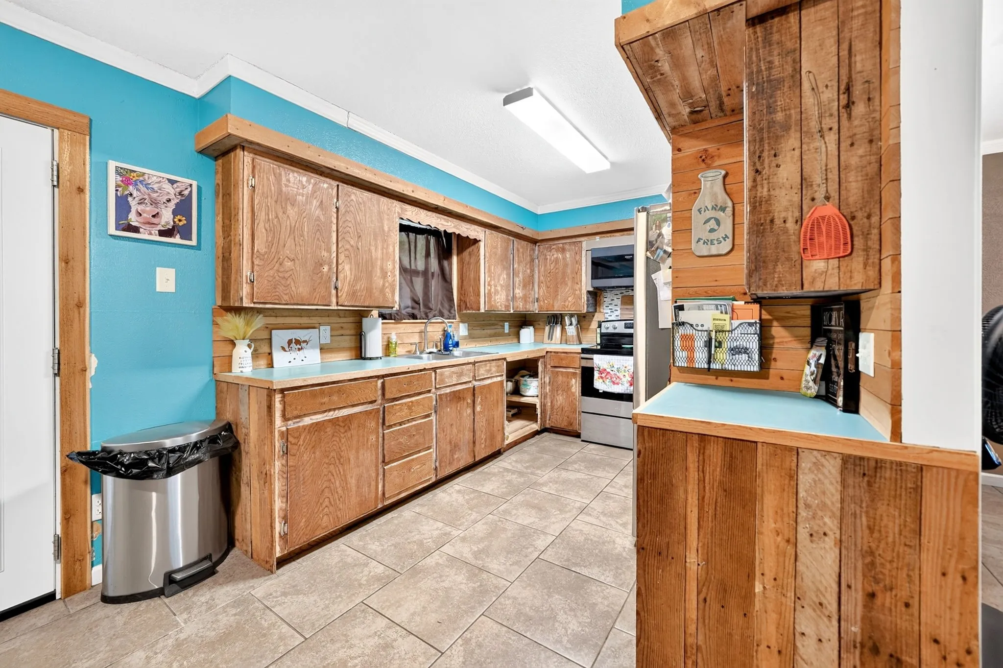 Kitchen featuring wood cabinetry, tiled flooring, stainless steel appliances, and a built-in breakfast bar