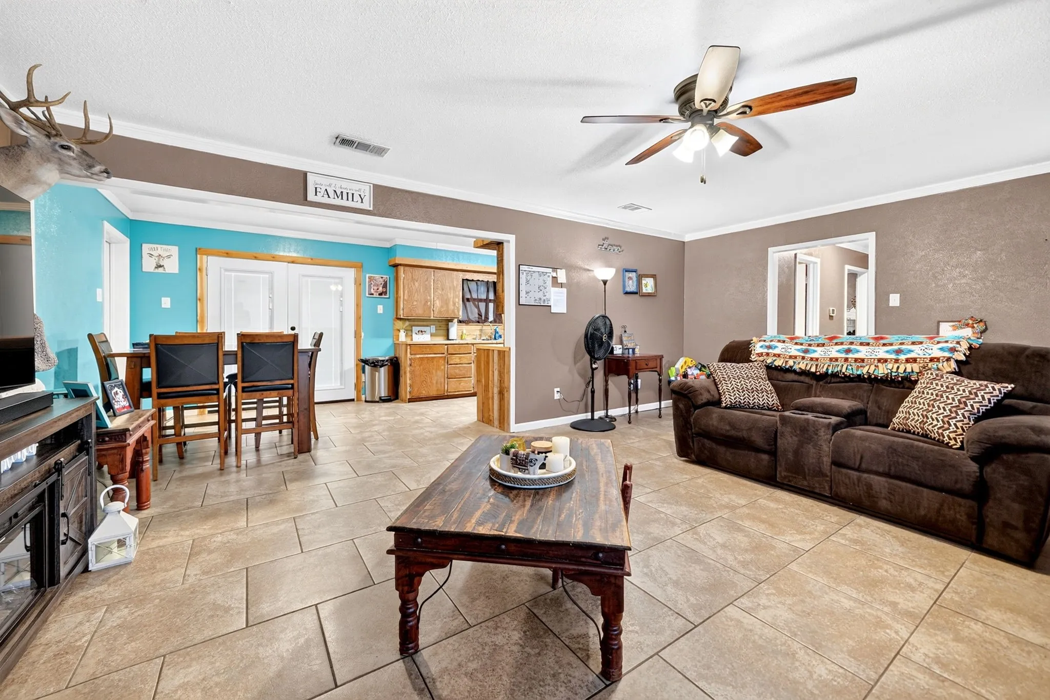Expansive tiled flooring spans the open living area, featuring a ceiling fan with light fixture