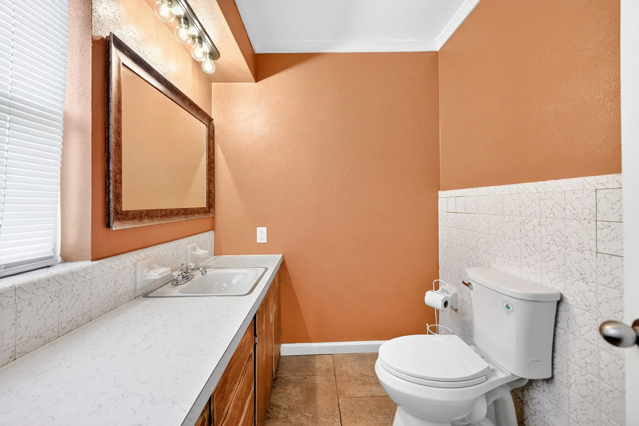 Bathroom featuring a vanity with a white countertop, an integrated sink, and wood-finish cabinetry