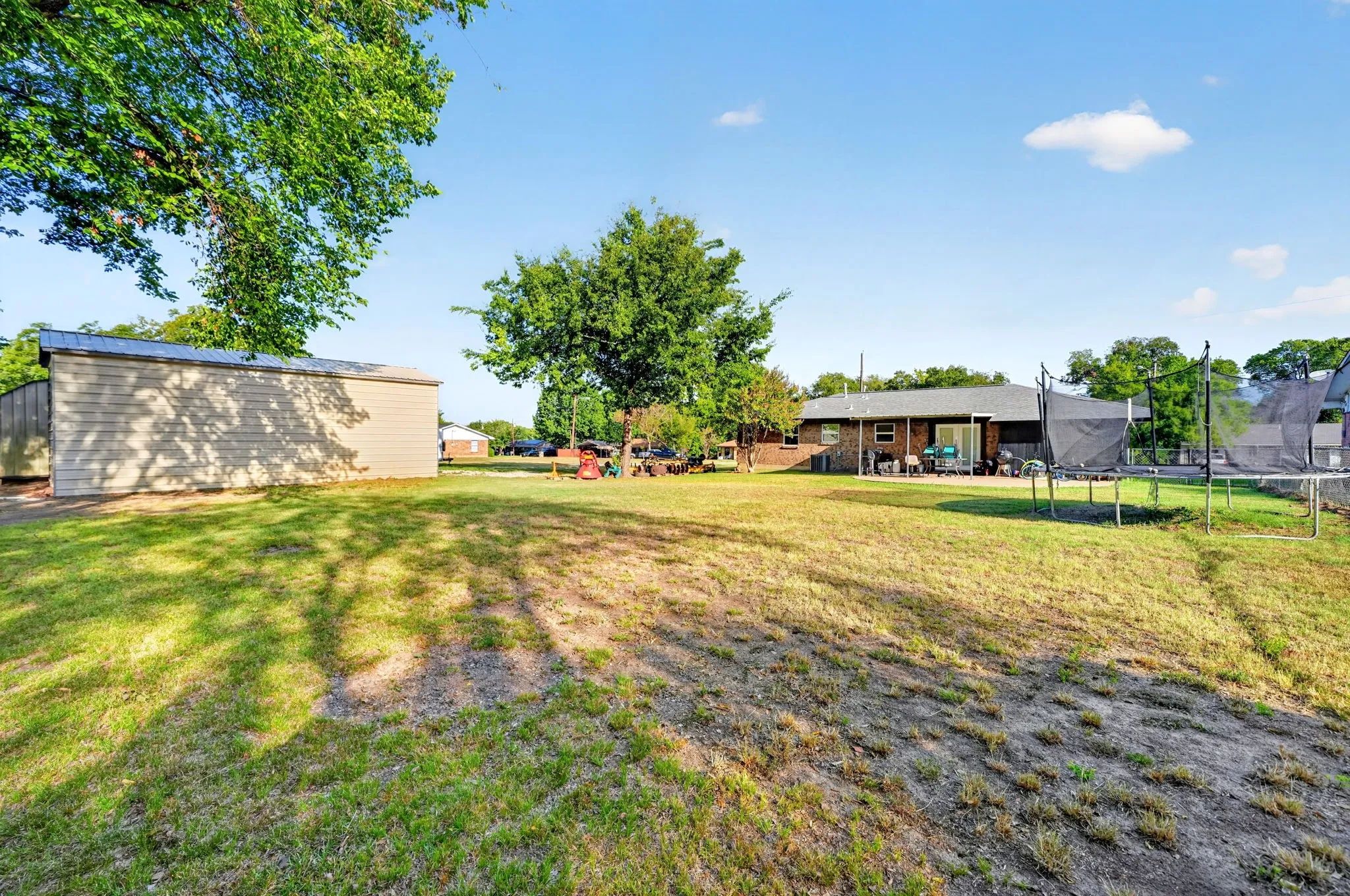Expansive backyard featuring a large lawn, mature trees, and a detached shed