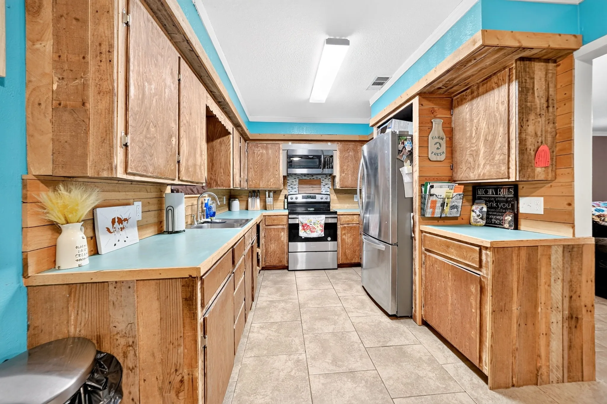 Kitchen featuring wood-panel cabinetry, light blue countertops, stainless steel appliances, and tile flooring