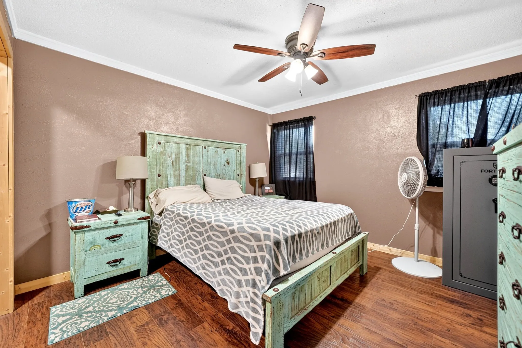 Wood-finish flooring with crown molding and a ceiling fan