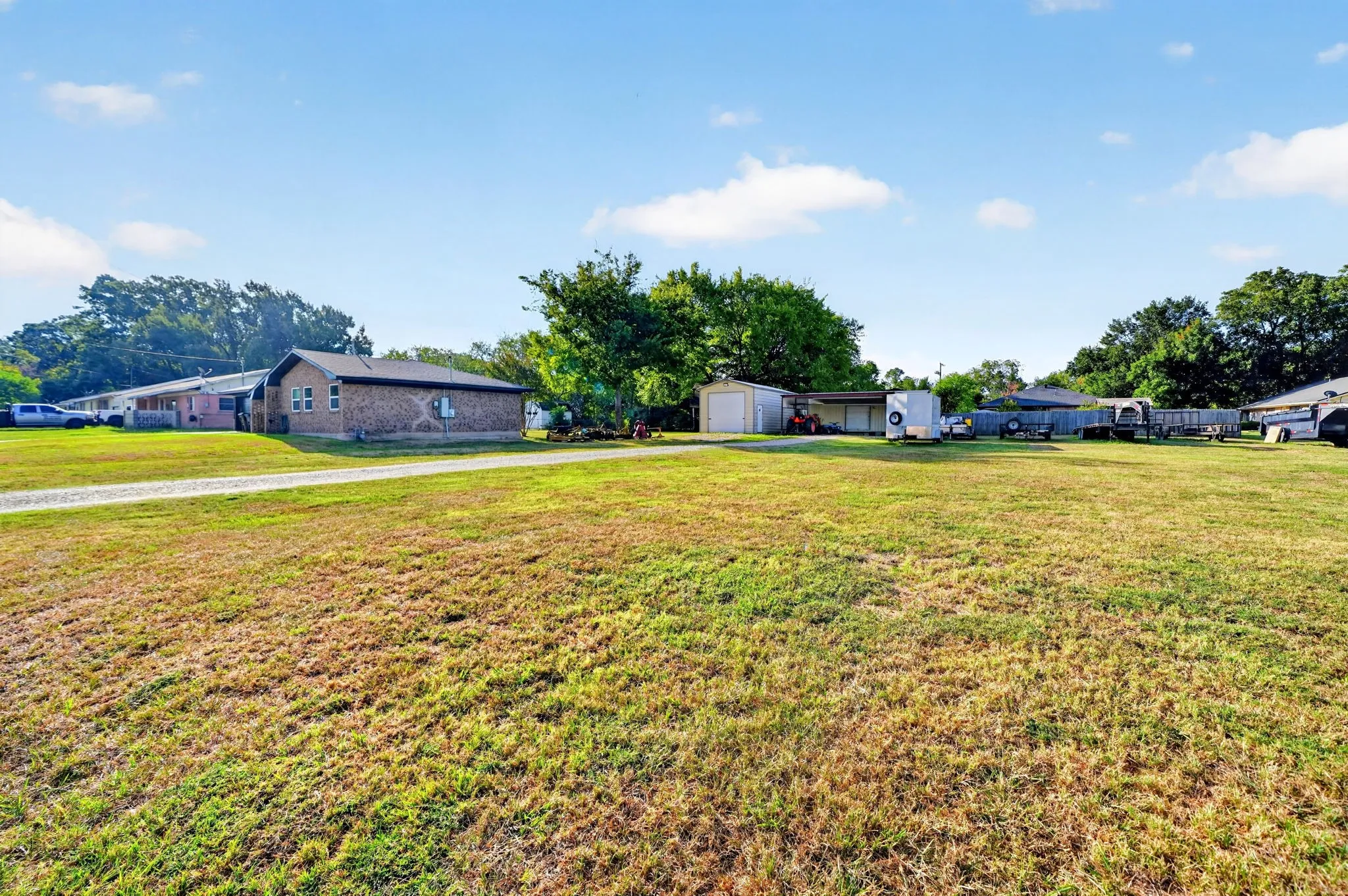 Expansive lot with a brick-clad residence, a detached garage, and a covered carport structure