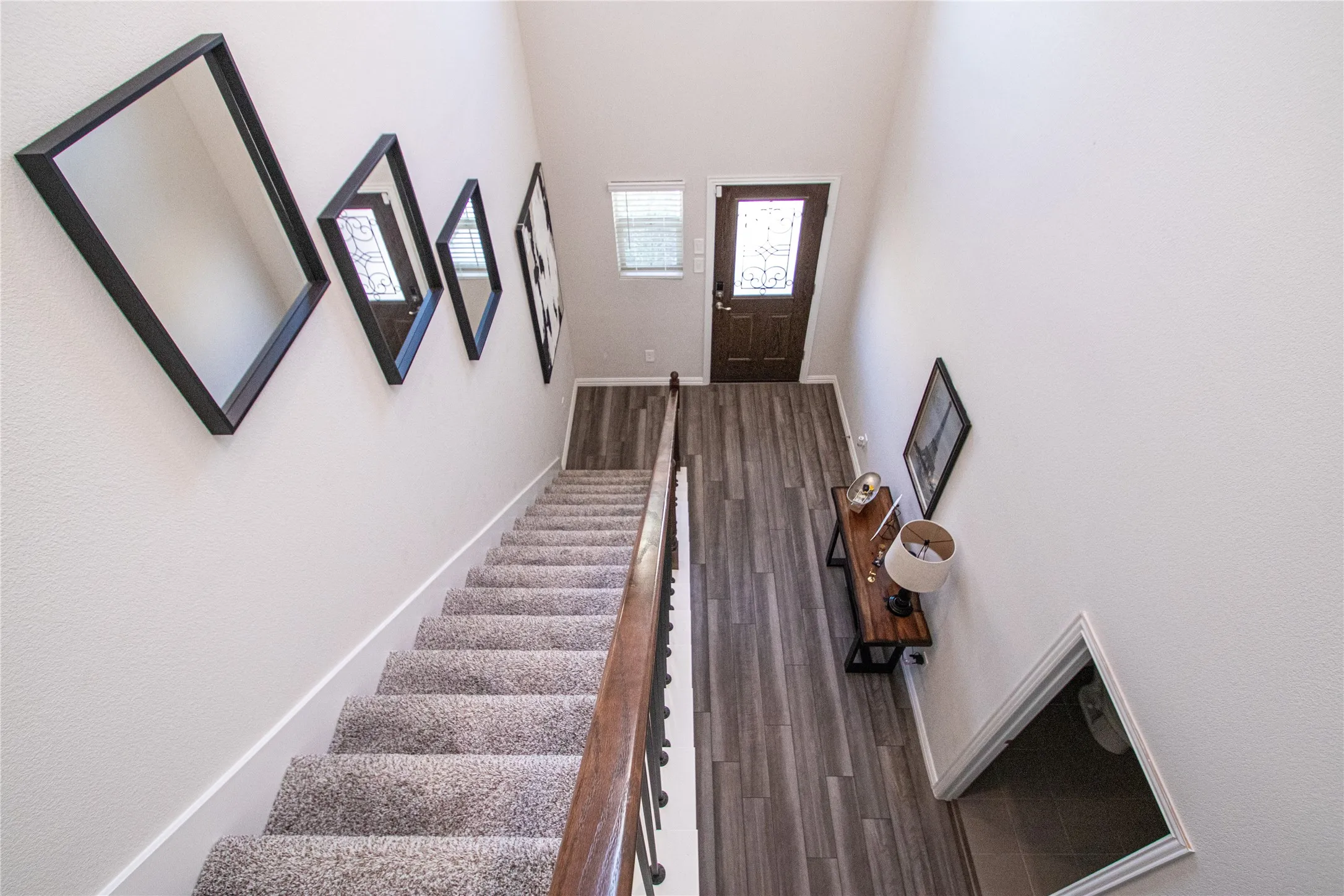 Two-story entryway featuring wood-finish flooring and a carpeted staircase with a wood handrail