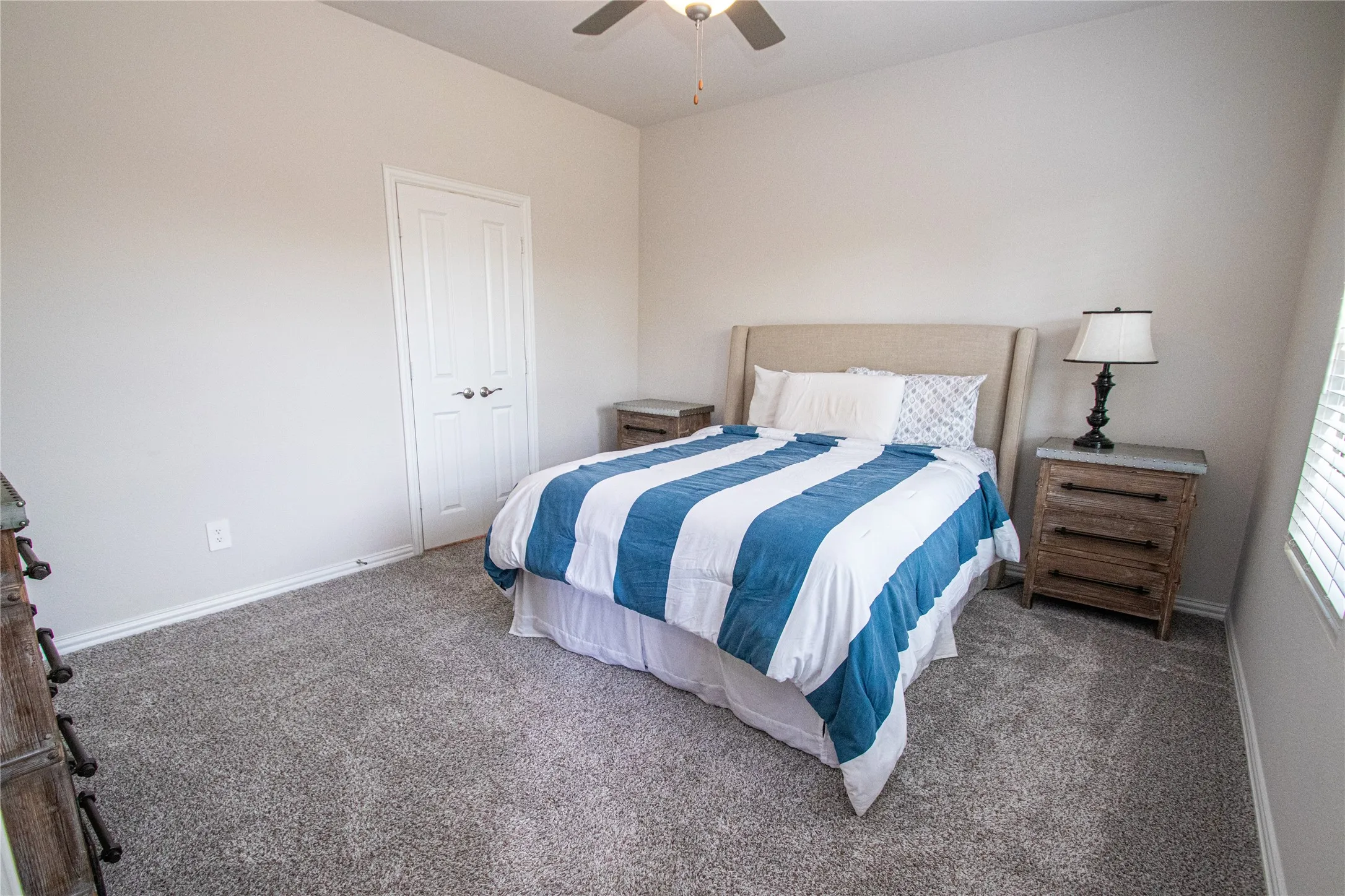 Neutral wall color, textured carpeting, double-door closet, ceiling fan with integrated lighting, and window with blinds