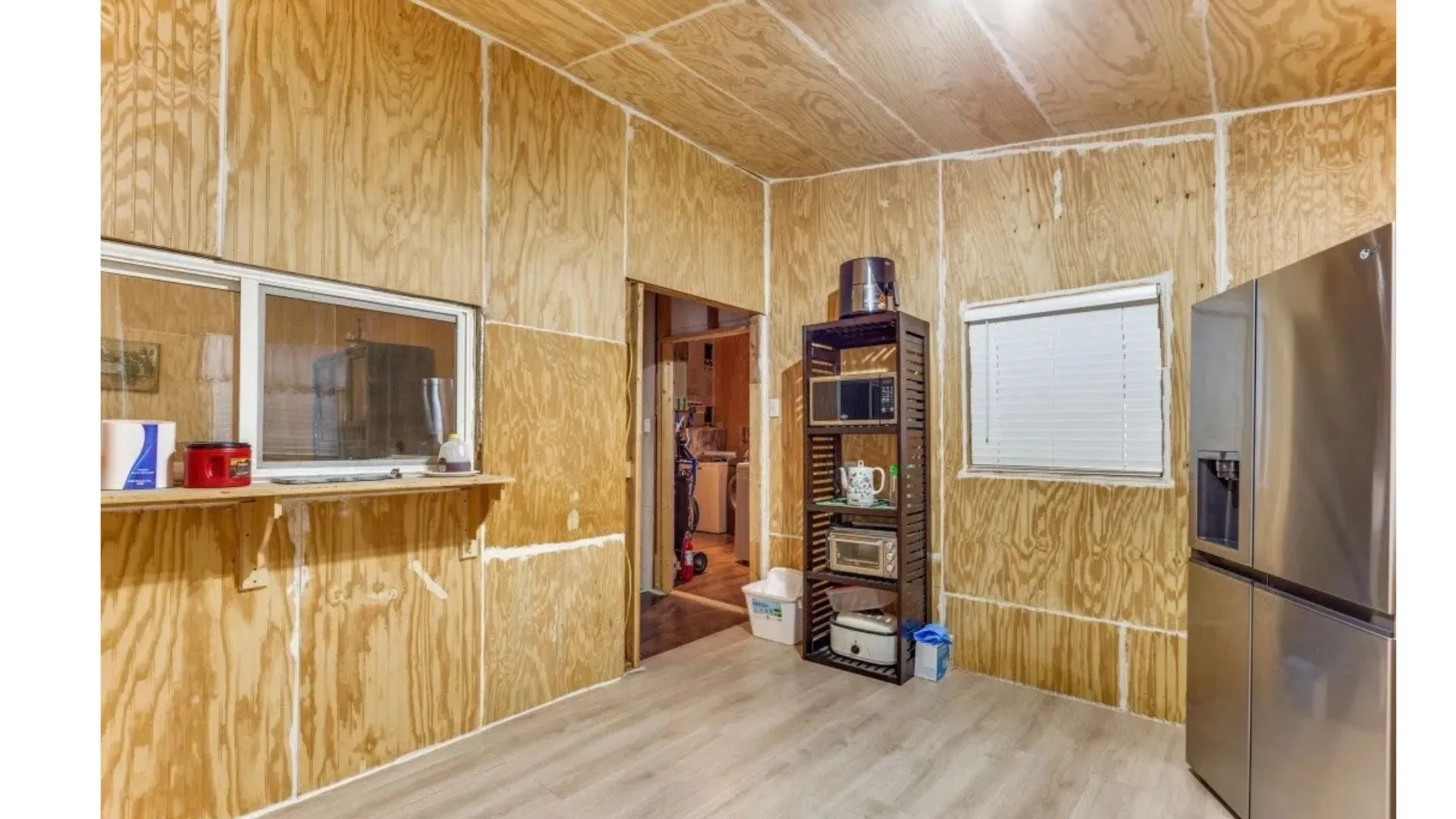 Wood-finish paneling throughout, light wood-finish flooring, and a stainless steel refrigerator