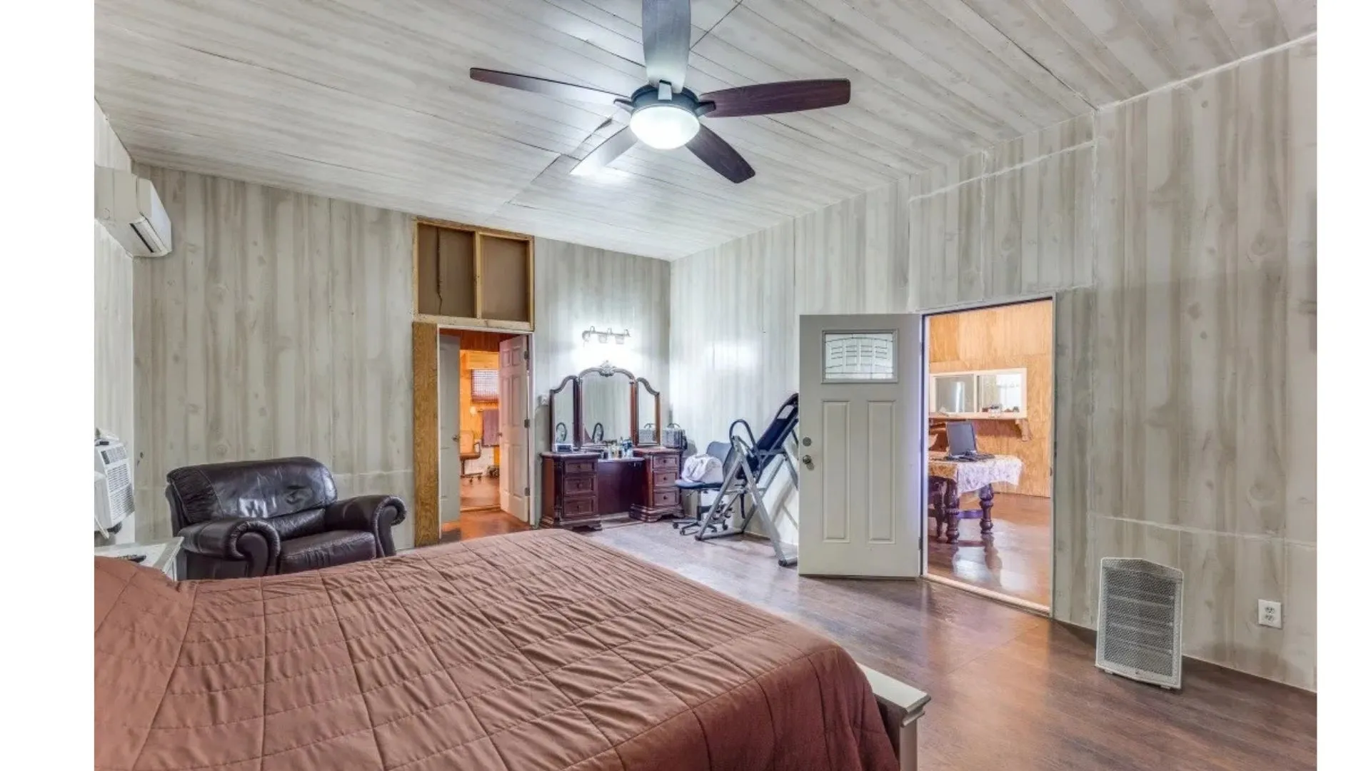 Angled wood-finish ceiling, wood-finish wall paneling, dark wood-finish flooring, and a ceiling fan with integrated lighting