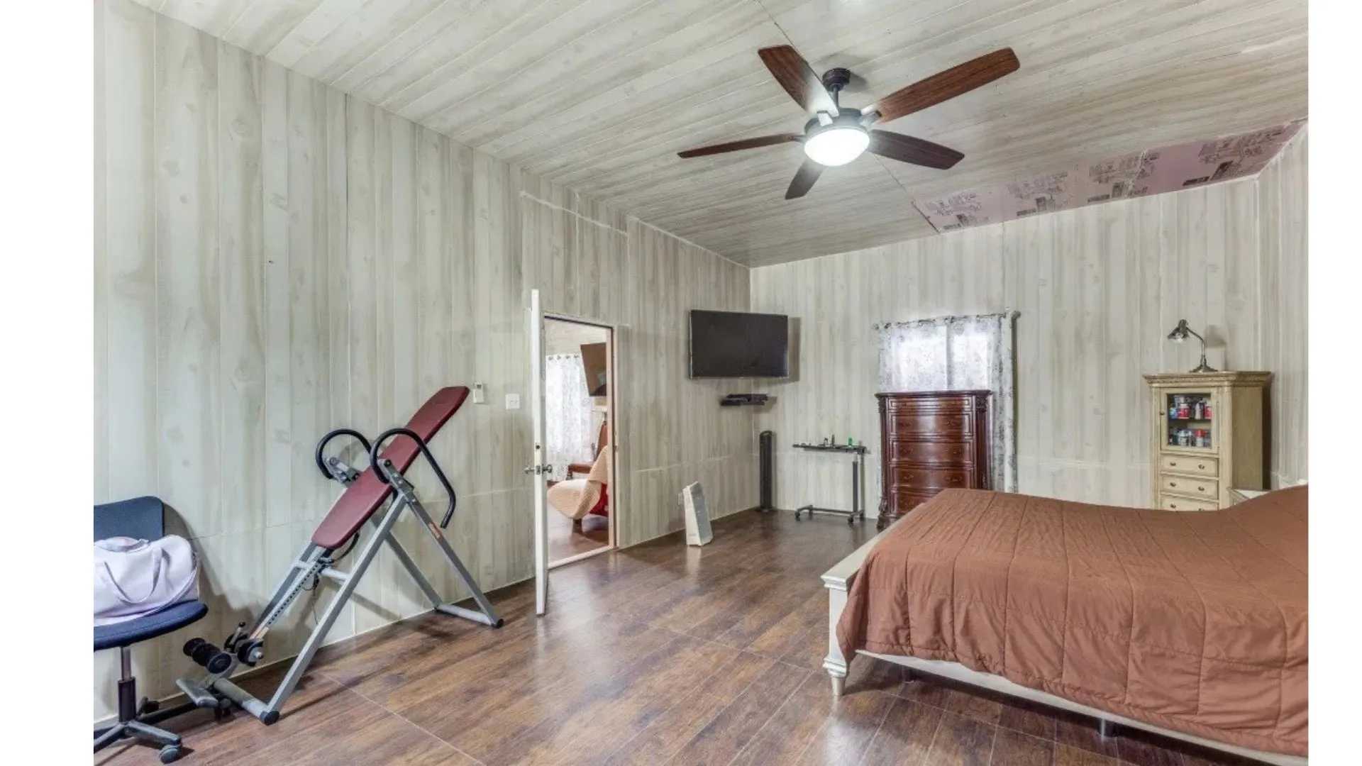 Wood-finish flooring, paneled walls, and a ceiling fan with integrated lighting