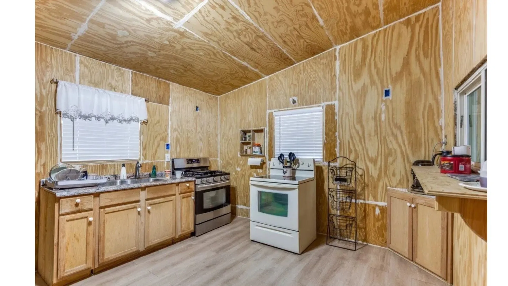 Wood-finish wall and ceiling panels, light wood-finish cabinetry, stainless steel gas range, and wood-finish flooring